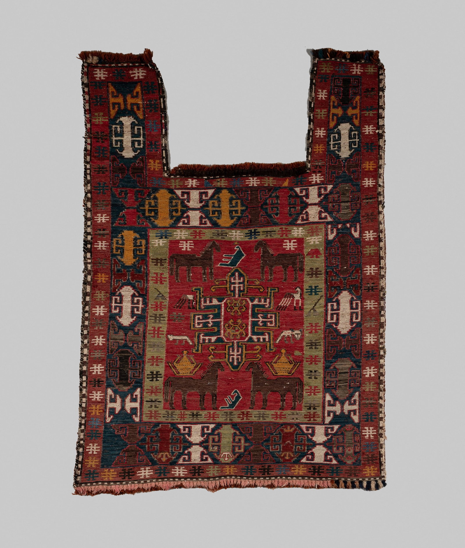 A PERSIAN SUMAK HORSE COVER: A PERSIAN SUMAK HORSE COVER Persia, early 20th century. Woven with a central panel depicting horses in alternating directions, framed by intricate borders of repeating geometric patterns, with the sma