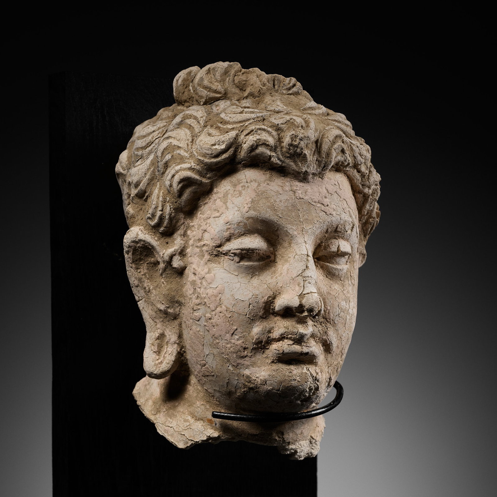 A RARE STUCCO HEAD OF MAITREYA, ANCIENT REGION OF GANDHARA, 3RD-4TH CENTURY: A RARE STUCCO HEAD OF MAITREYA, ANCIENT REGION OF GANDHARA, 3RD-4TH CENTURY Finely modeled, the well-rounded face with half-opened almond-shaped eyes, aquiline nose, and bow-shaped pursed lips forming