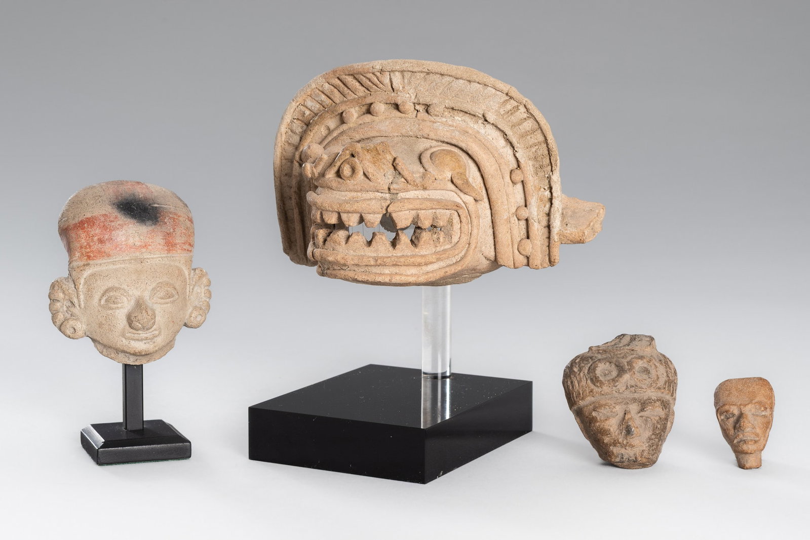 A GROUP OF FOUR PRE-COLUMBIAN POTTERY HEADS: A GROUP OF FOUR PRE-COLUMBIAN POTTERY HEADS 1st Millenium AD. Comprising four heads, including two small heads of men, a larger human head, and a larger zoomorphic head. One of the small human heads b