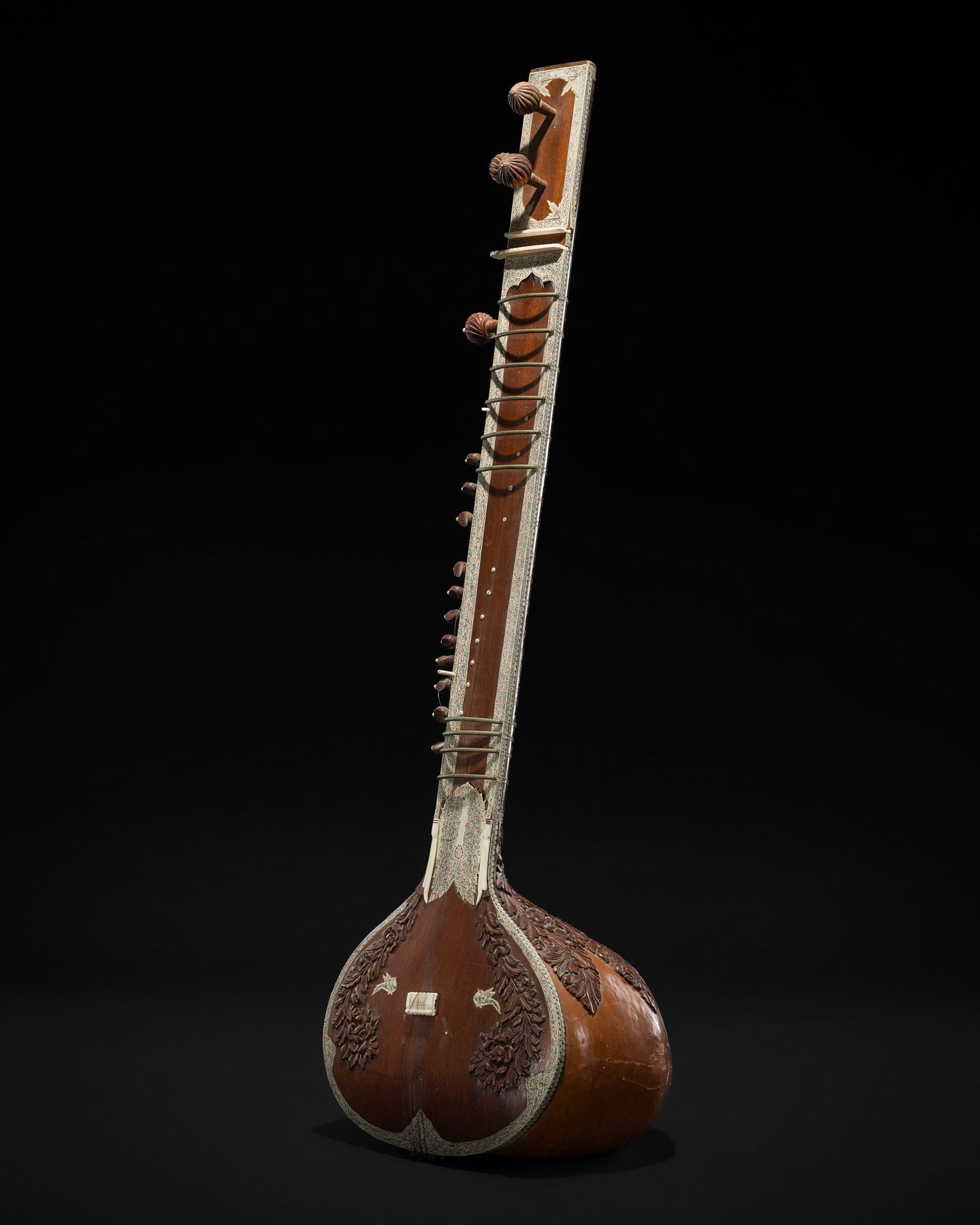 A BONE INLAID CARVED WOOD SITAR, PROBABLY BY RADHA KRISHNA SHARMA & CO., 20TH CENTURY: A BONE INLAID CARVED WOOD SITAR, PROBABLY BY RADHA KRISHNA SHARMA & CO., 20TH CENTURY This lot is a museum deaccession and is therefore offered without reserve India. The gourd-shaped body (tumba) ri