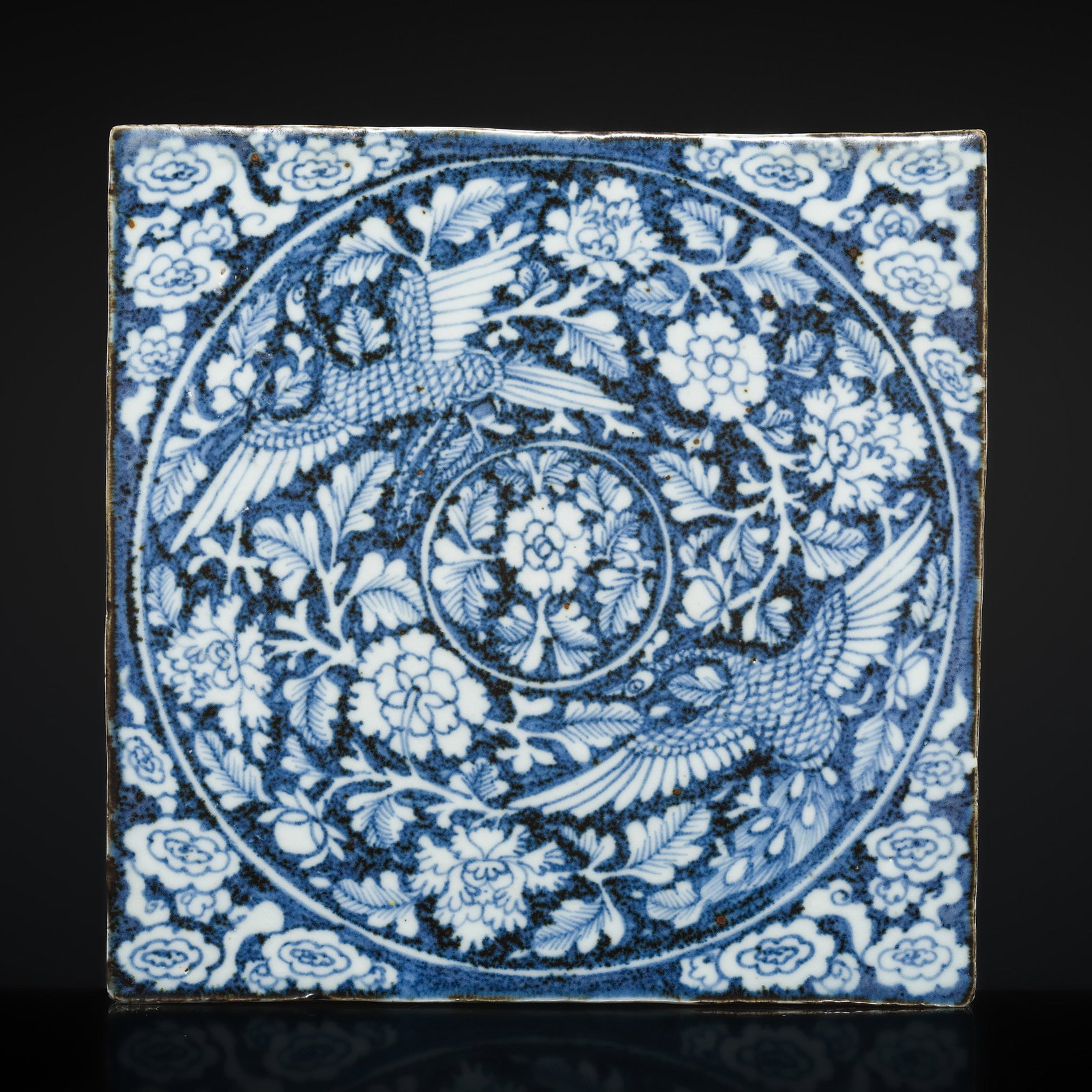 A RARE BLUE AND WHITE 'PHOENIX' TILE, LATE MING DYNASTY: A RARE BLUE AND WHITE 'PHOENIX' TILE, LATE MING DYNASTY China, 16th-17th century. Massively potted and finely painted in well graduated shades of deep cobalt blue with a central peony medallion encirc