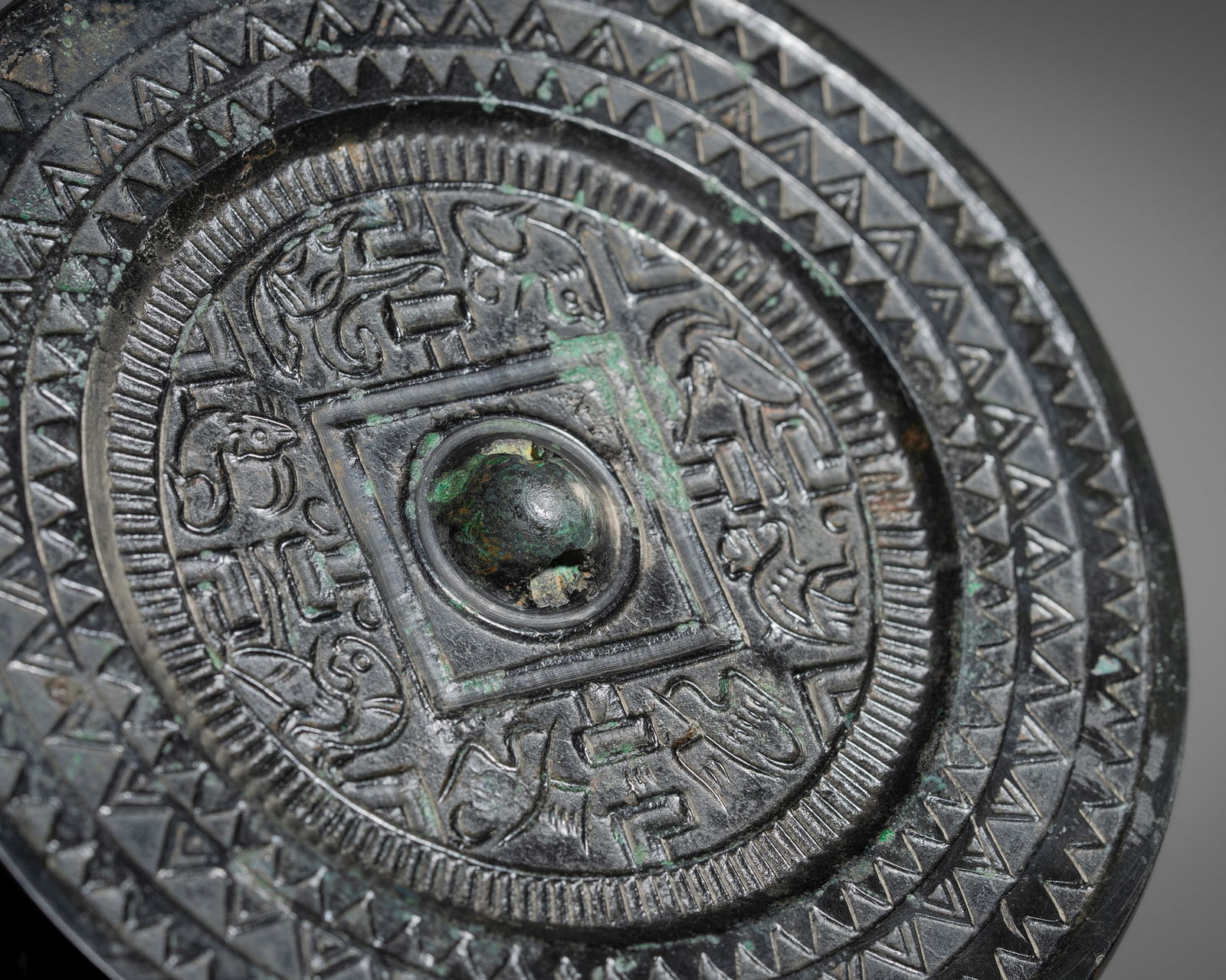 A 'TLV' BRONZE MIRROR, HAN DYNASTY: A 'TLV' BRONZE MIRROR, HAN DYNASTY China, 206 BC-AD 220. Finely cast, the central knob is enclosed within a square border from which extend four 'T'-shaped motifs. Around this are arranged mythical be
