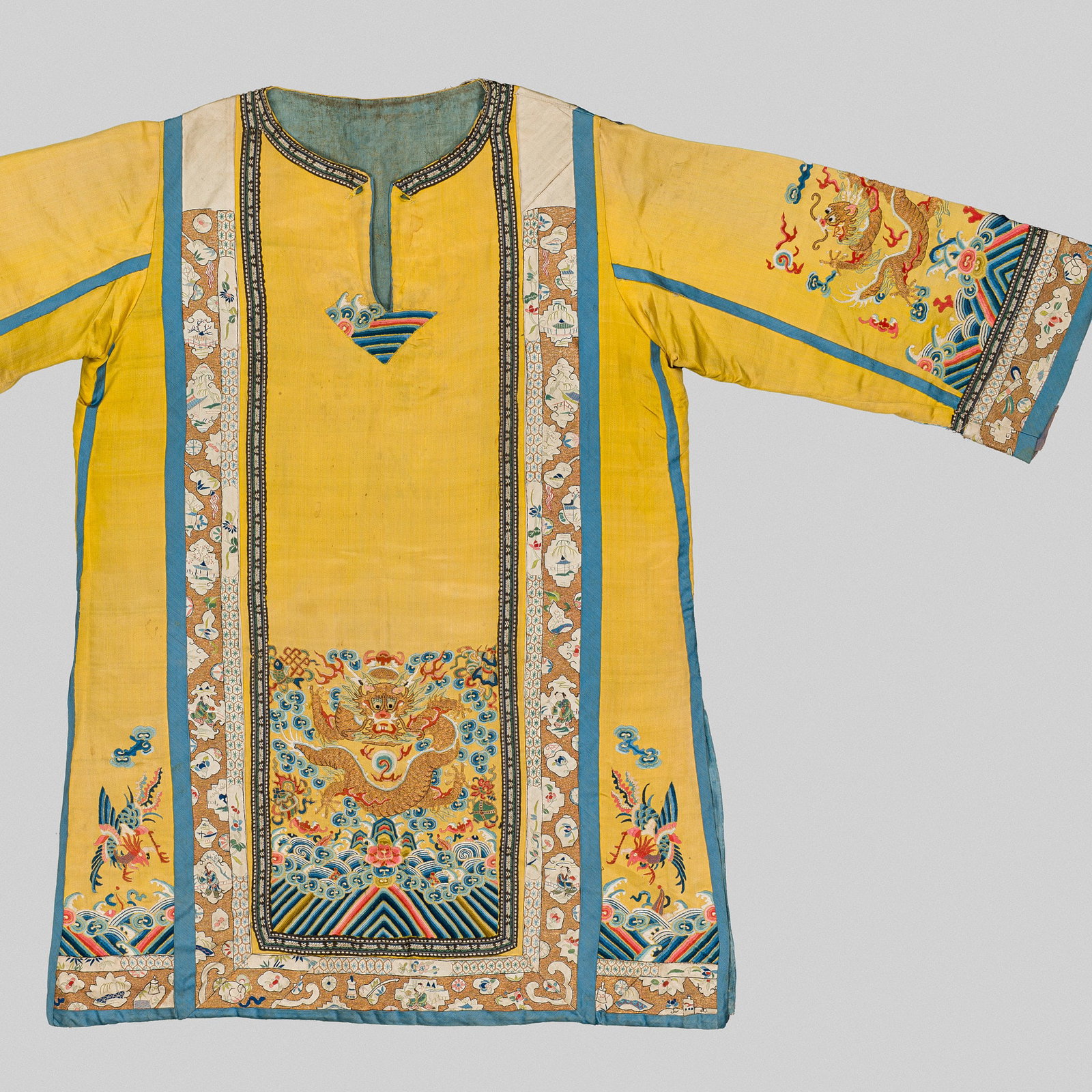 A YELLOW SILK EMBROIDERED 'DRAGON' TUNIC, QING DYNASTY: A YELLOW SILK EMBROIDERED 'DRAGON' TUNIC, QING DYNASTY China, late 19th century. The imperial yellow silk ground finely embroidered with gilt-wrapped thread, satin stitch, and Bejing knot, the front d