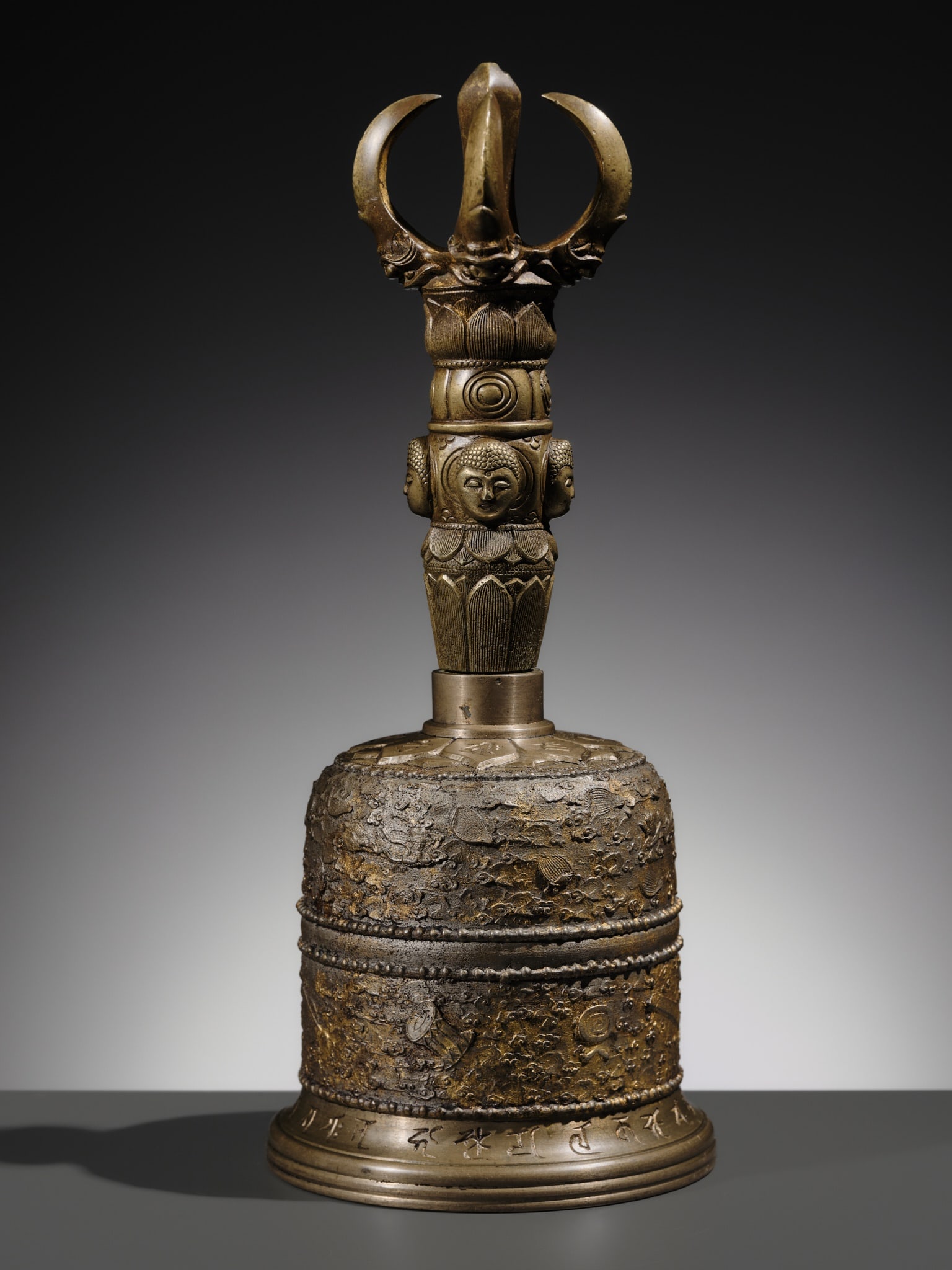 AN UNUSUAL AND LARGE PARCEL-GILT BRONZE FOUR-PRONGED VAJRA BELL: AN UNUSUAL AND LARGE PARCEL-GILT BRONZE FOUR-PRONGED VAJRA BELL Japan, 19th century and laterThe handle is cast as a four-pronged vajra, featuring a central knop adorned with four Buddha heads and fur