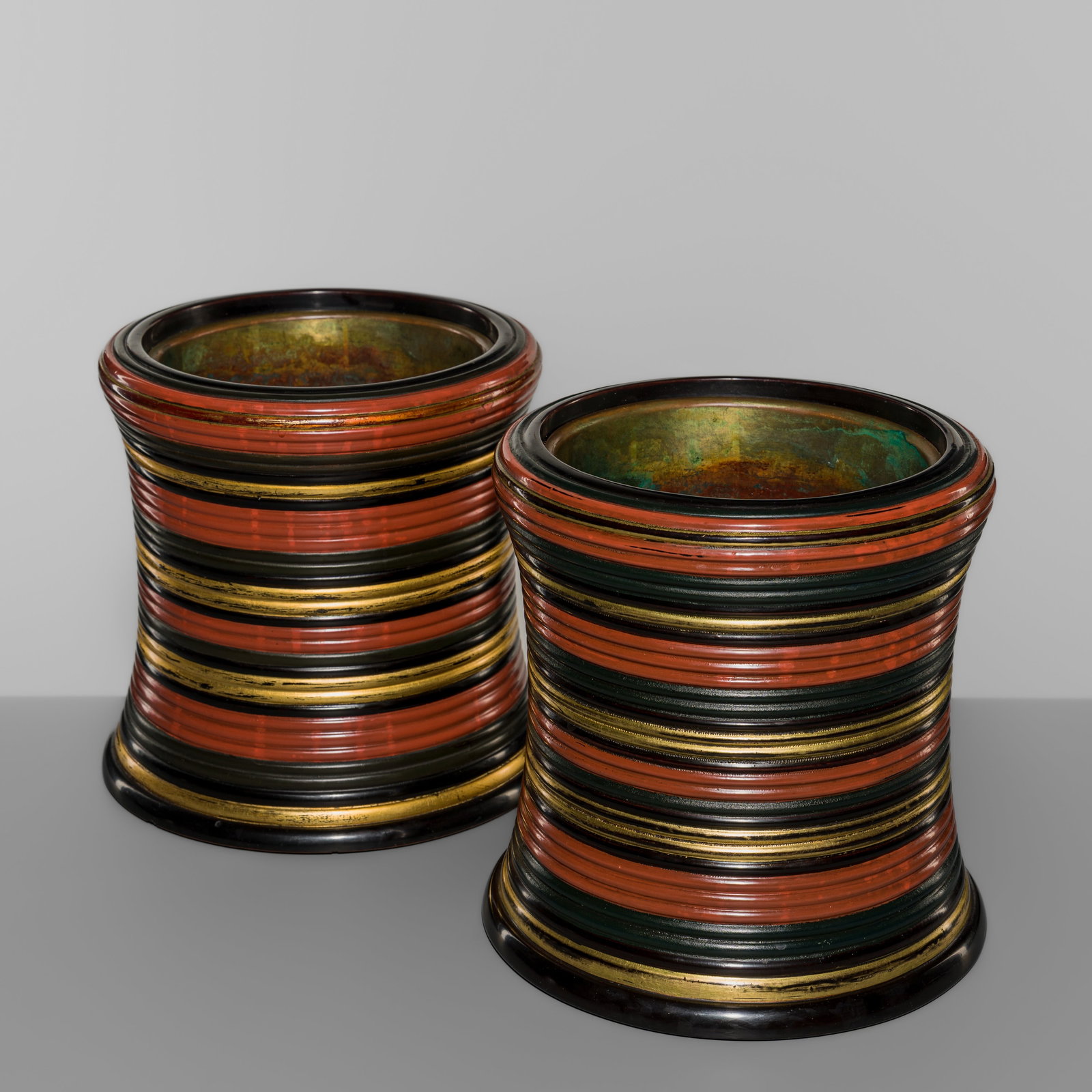 A PAIR OF LACQUER WOOD AND COPPER HIBACHI (BRAZIER): A PAIR OF LACQUER WOOD AND COPPER HIBACHI (BRAZIER) Japan, 20th centuryOf cylindrical, slightly convex form, each brazier carved from wood and encircled by alternating horizontal bands of red, black,