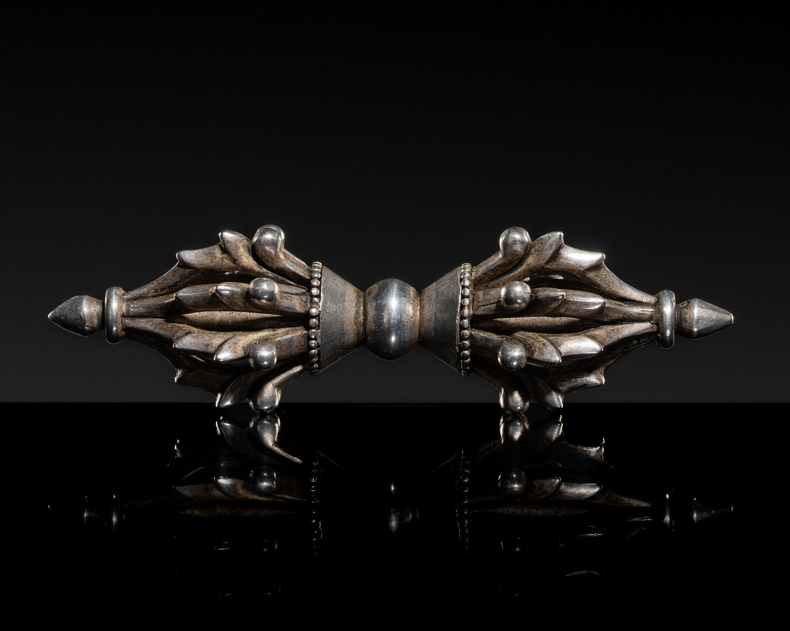 A SMALL WHITE METAL VAJRA, TIBET, 20TH CENTURY: A SMALL WHITE METAL VAJRA, TIBET, 20TH CENTURY Boldly cast, the narrow eight-pronged vajra with a central knob flanked by conical collars with beaded borders, each incised with lotus petals, from whic