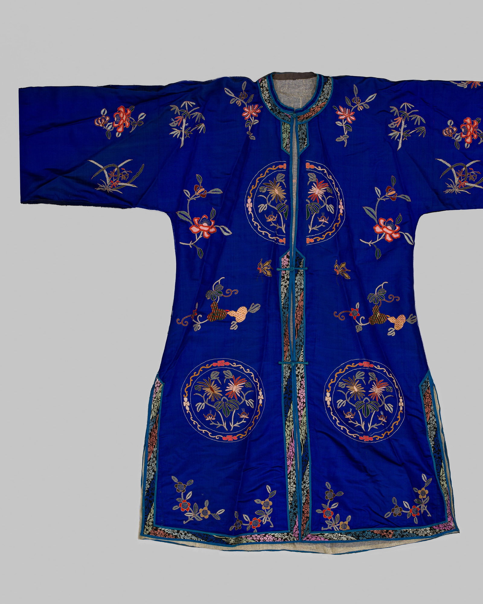 AN EMBROIDERED BLUE SILK LONGGUA WOMAN'S SURCOAT WITH FOLIATE ROUNDELS, LATE QING DYNASTY (1 of 8)