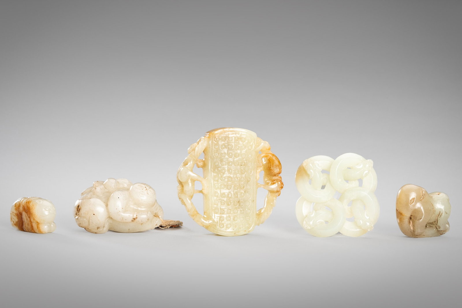 A GROUP OF FIVE PALE CELADON AND GRAY JADE PENDANTS, QING DYNASTY AND EARLIER: A GROUP OF FIVE PALE CELADON AND GRAY JADE PENDANTS, QING DYNASTY AND EARLIER China, Qing Dynasty (1644-1912) and earlier. Comprising three pale celadon and two gray jade pendants. The first Han-style
