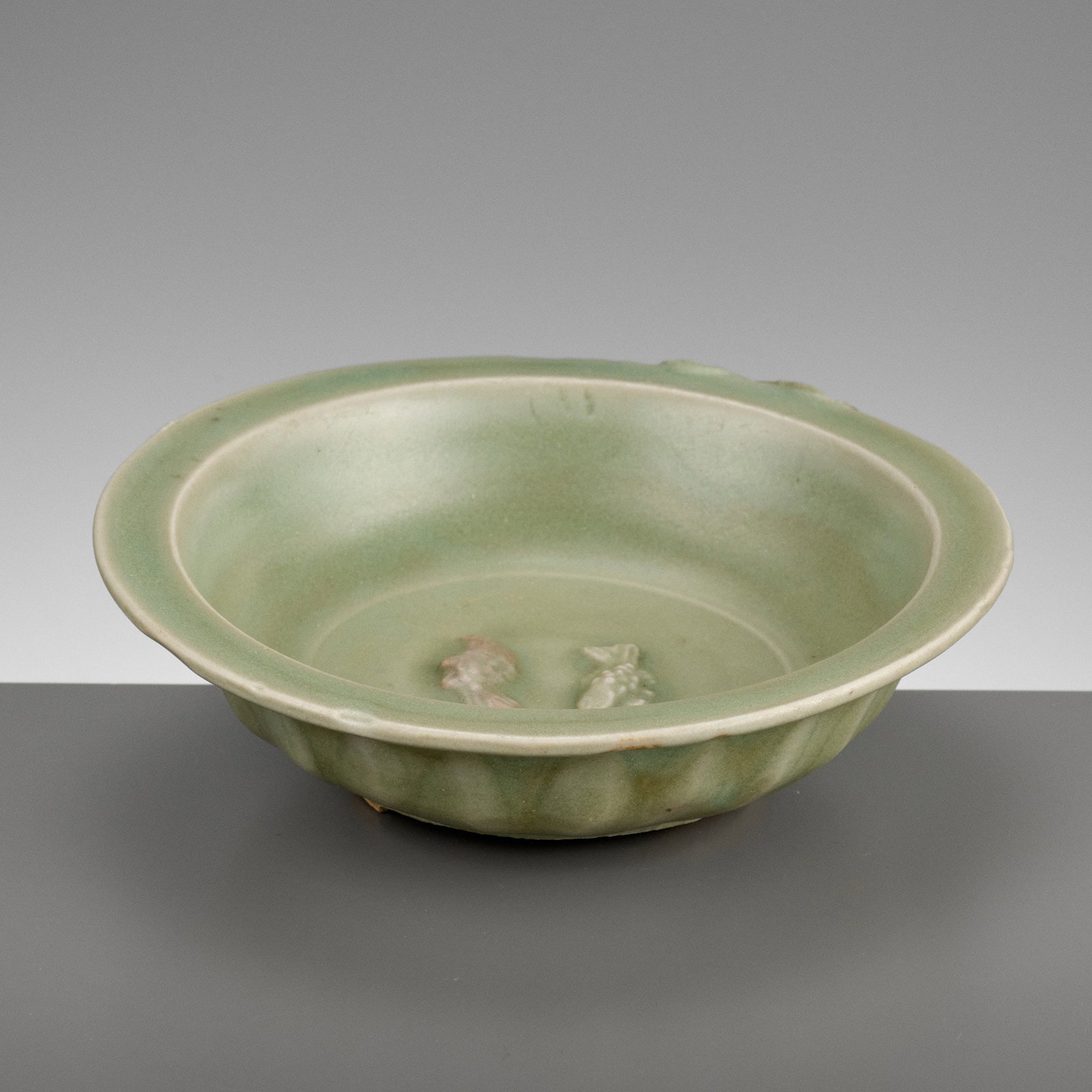 A LONGQUAN CELADON 'TWIN FISH' DISH, SOUTHERN SONG TO YUAN DYNASTY: A LONGQUAN CELADON 'TWIN FISH' DISH, SOUTHERN SONG TO YUAN DYNASTY China, 13th-14th century. The exterior of the deep rounded sides carved with a band of petals rising from the foot to the flat everte