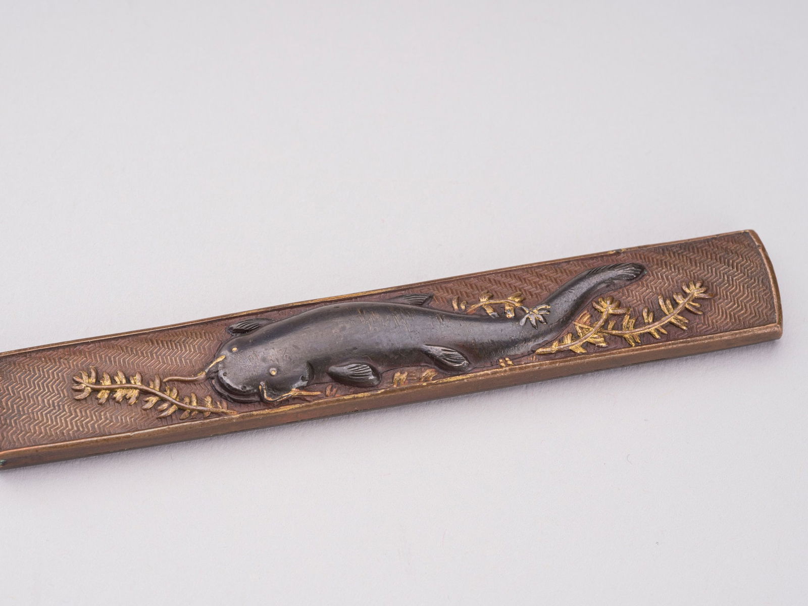 A FINE COPPER, SHIBUICHI, AND GOLD KOZUKA WITH A NAMAZU, EDO: A FINE COPPER, SHIBUICHI, AND GOLD KOZUKA WITH A NAMAZU, EDO Japan, 19th century, Edo period (1615-1868). One side decorated in shibuichi and gold takazogan with a namazu (catfish) amid water weeds ab