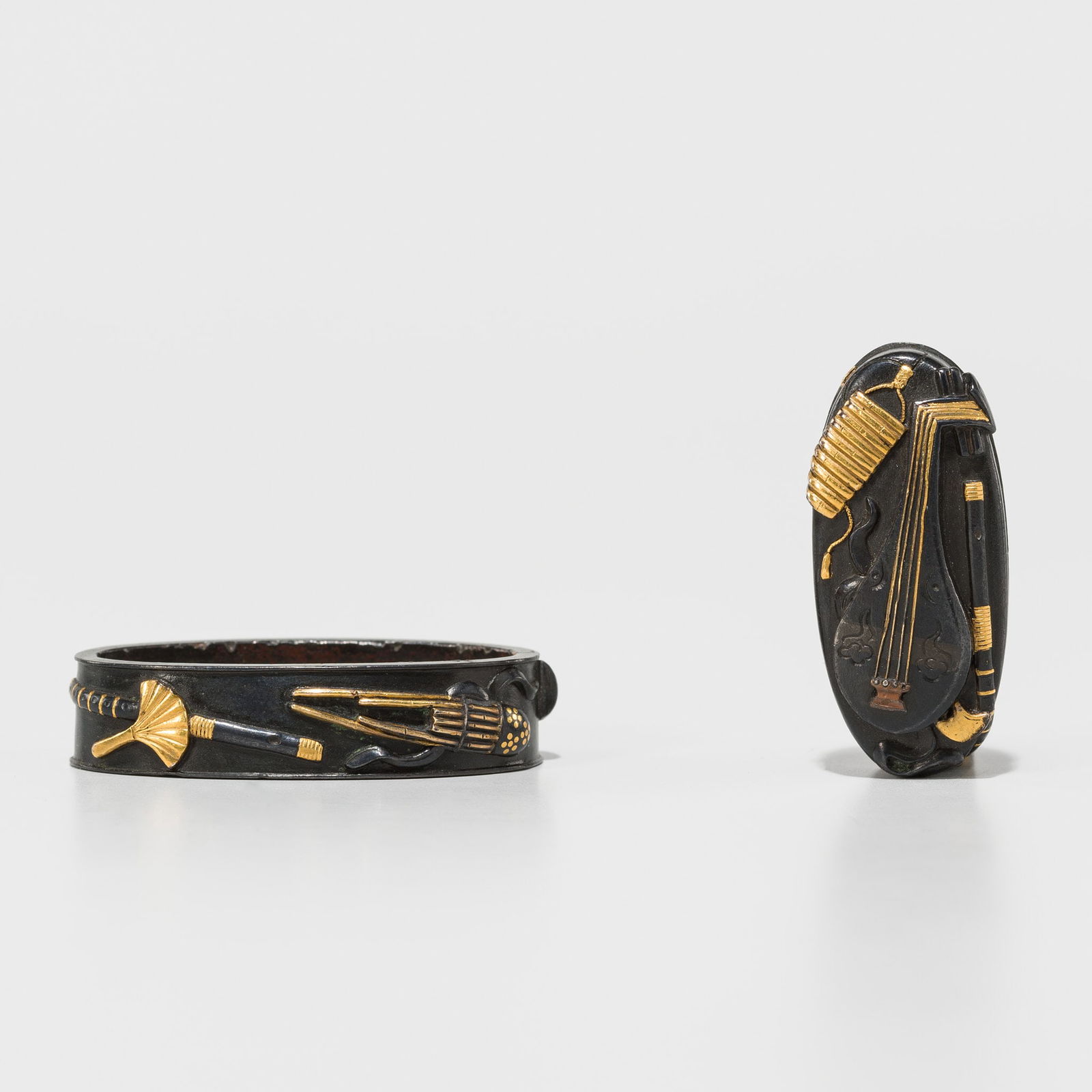 A RARE SHIBUICHI FUCHI AND KASHIRA DEPICTING MUSICAL INSTRUMENTS: A RARE SHIBUICHI FUCHI AND KASHIRA DEPICTING MUSICAL INSTRUMENTS UnsignedJapan, 19th century, Edo period (1615-1868)Finely worked on a migakiji (polished) shibuichi ground in gold, shibuichi, and sh