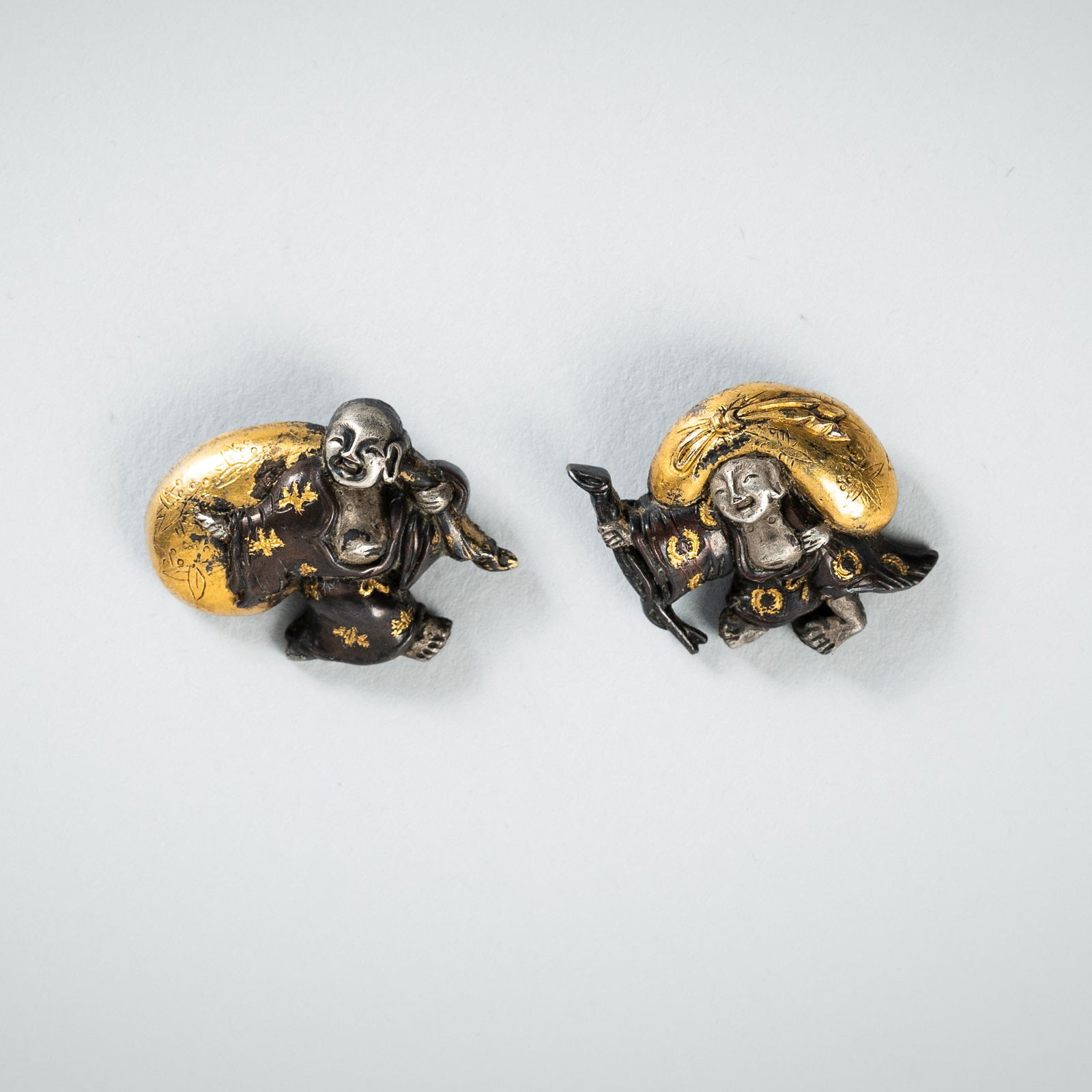 A PAIR OF SHIBUICHI MENUKI DEPICTING HOTEI WITH HIS TREASURE BAG (1 of 3)