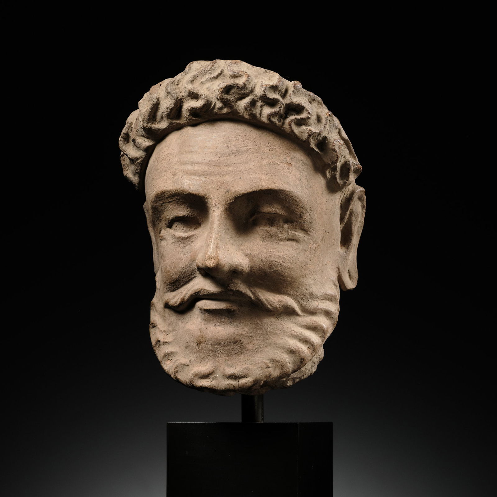 A TERRACOTTA HEAD OF VAJRAPANI IN THE FORM OF HERACLES, ANCIENT REGION OF GANDHARA, 4TH-5TH CENTURY (1 of 12)