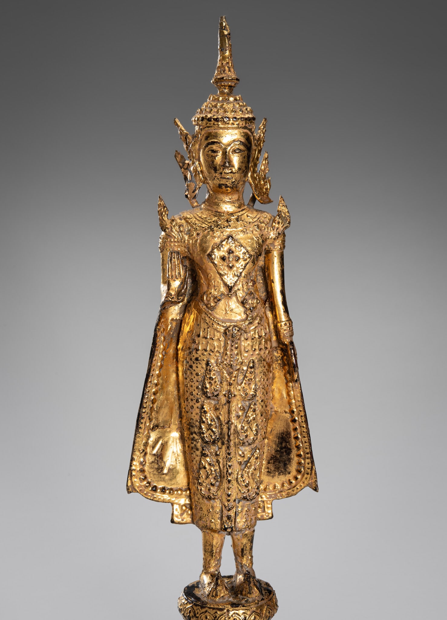 A GILT-BRONZE FIGURE OF BUDDHA, RATTANAKOSIN KINGDOM, 19TH CENTURY: A GILT-BRONZE FIGURE OF BUDDHA, RATTANAKOSIN KINGDOM, 19TH CENTURY Thailand. Standing in samabhanga on a multi-tiered octagonal base decorated with beaded bands. The Buddha holds his right hand in abh