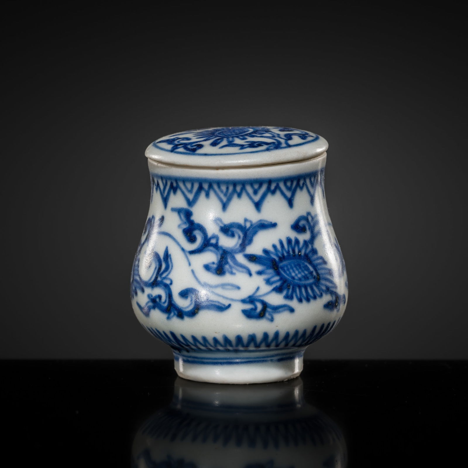 A MINIATURE BLUE AND WHITE 'CHRYSANTHEMUM' JAR AND COVER, TRANSITIONAL PERIOD, FROM THE HATCHER: A MINIATURE BLUE AND WHITE 'CHRYSANTHEMUM' JAR AND COVER, TRANSITIONAL PERIOD, FROM THE HATCHER CARGO China, c. 1643-1645. Finely potted, the jarlet rising from a small, ring foot to a gently swellin