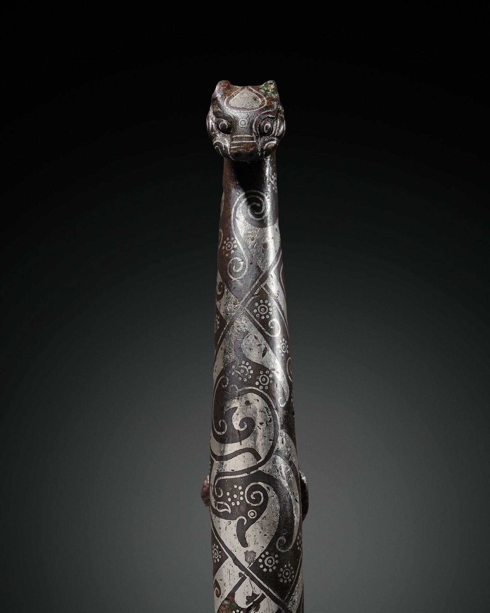 A SILVER-INLAID BRONZE GARMENT HOOK, DAIGOU, WARRING STATES-HAN DYNASTY: A SILVER-INLAID BRONZE GARMENT HOOK, DAIGOU, WARRING STATES-HAN DYNASTY China, 4th-1st century BC. The slender, rounded shaft intricately inlaid with silver sheet and wire, forming overlapping and in