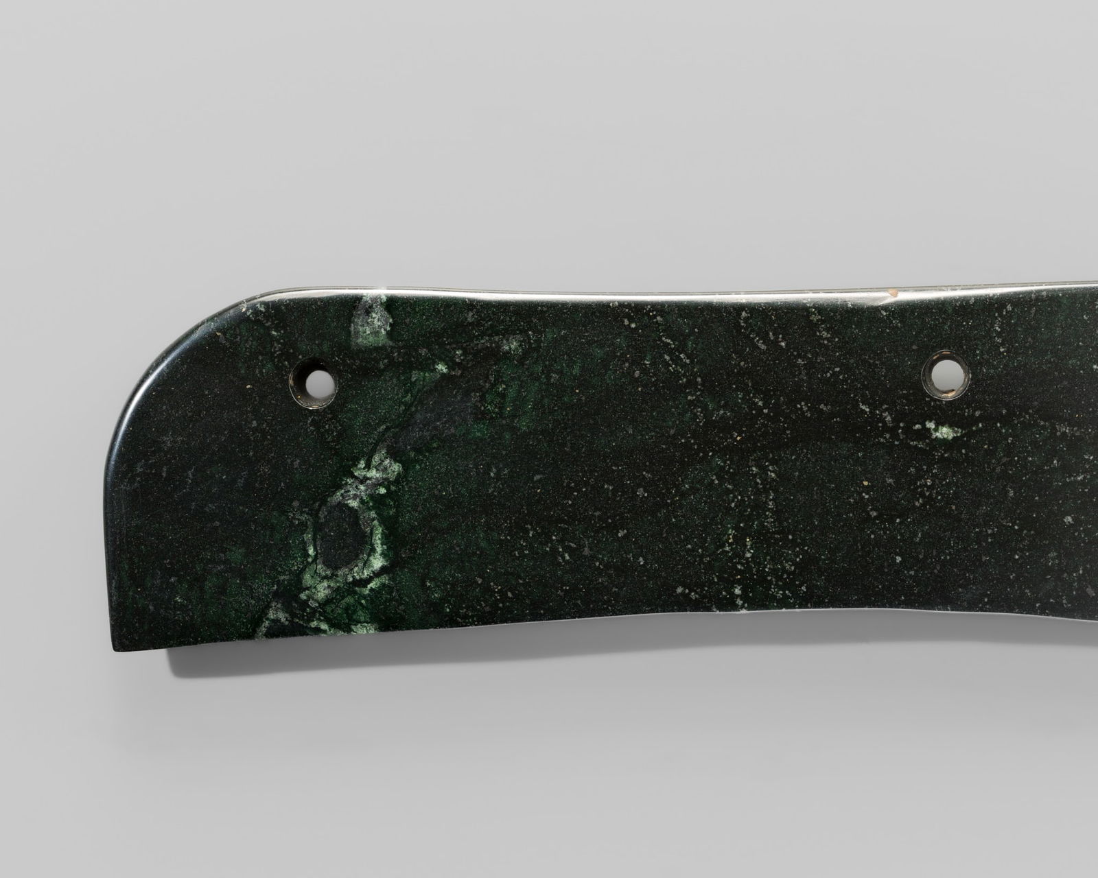 A DARK GREEN CEREMONIAL REAPING KNIFE, LATE NEOLITHIC PERIOD, LONGSHAN CULTURE: A DARK GREEN CEREMONIAL REAPING KNIFE, LATE NEOLITHIC PERIOD, LONGSHAN CULTURE China, c. 2500-2200 BC. Of rectangular form, thinly carved, with the long edges slightly convex, one corner distinctly r