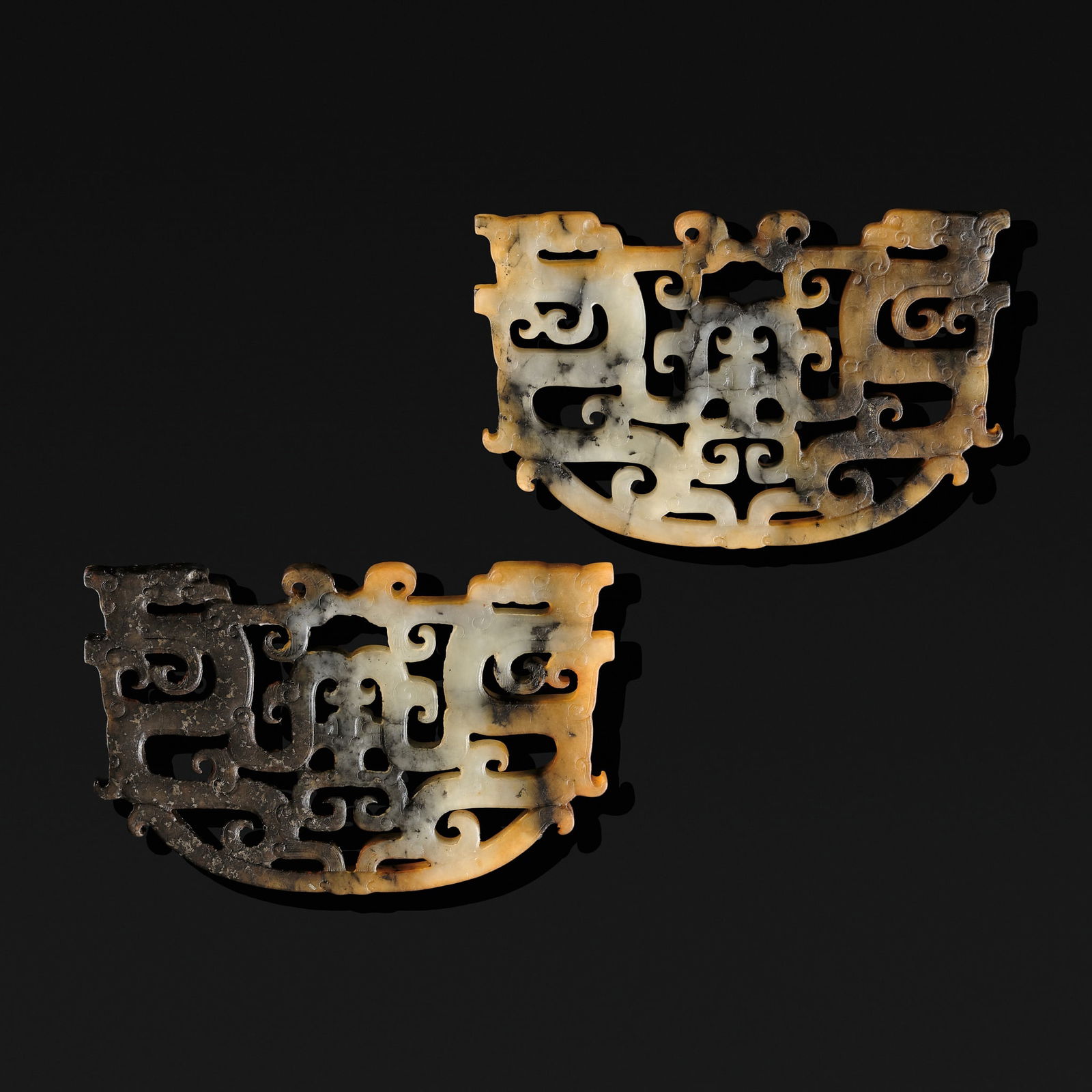 A PAIR OF WHITE, RUSSET, AND BROWN JADE 'DRAGON AND PHOENIX' PENDANTS, EASTERN ZHOU DYNASTY, WARRING: A PAIR OF WHITE, RUSSET, AND BROWN JADE 'DRAGON AND PHOENIX' PENDANTS, EASTERN ZHOU DYNASTY, WARRING STATES PERIOD China, 475-221 BC. Each of slightly trapezoidal form with a curved edge, masterfully