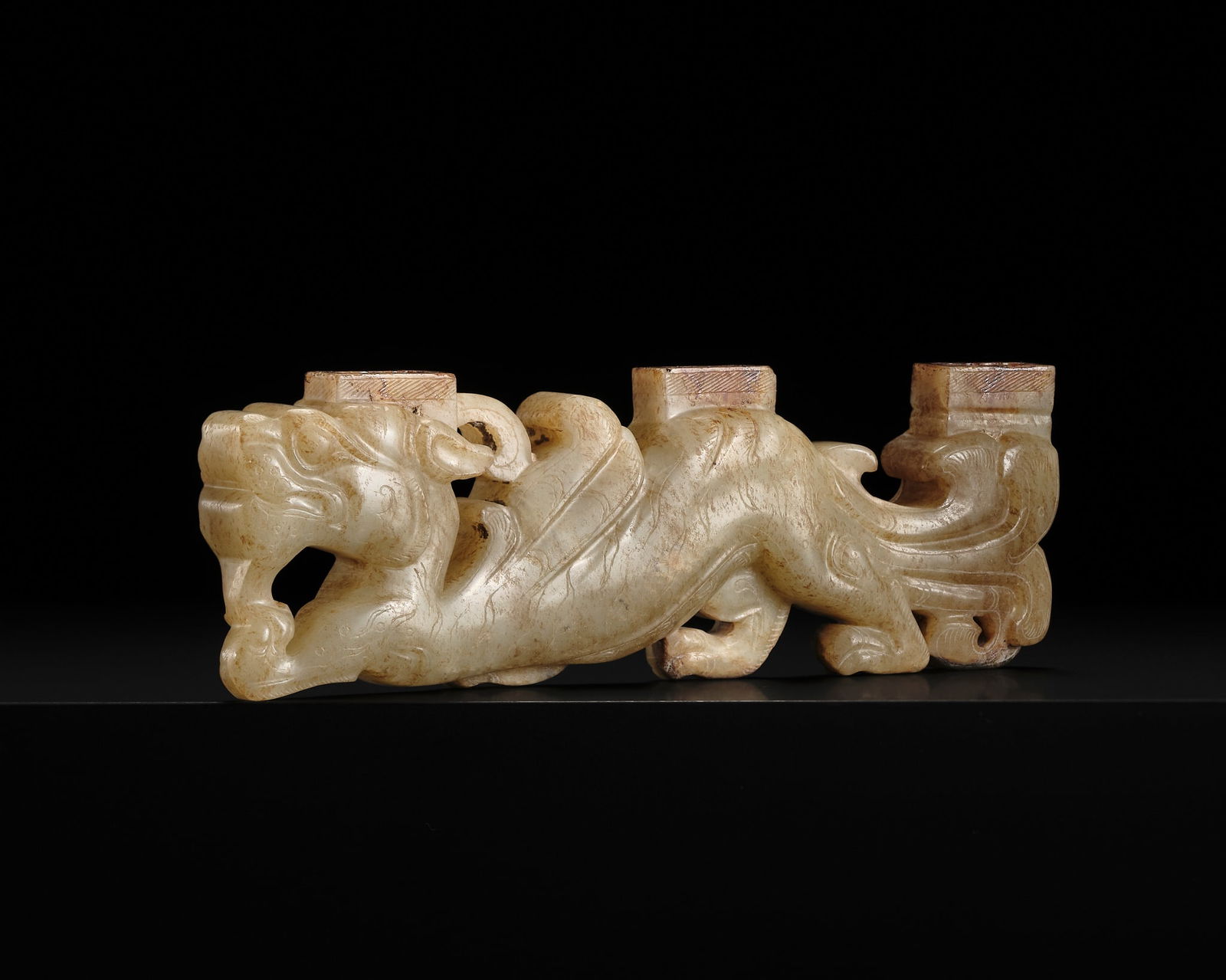 A RARE AND UNUSUAL THREE-TIERED JADE 'DRAGON' FITTING, HAN DYNASTY: A RARE AND UNUSUAL THREE-TIERED JADE 'DRAGON' FITTING, HAN DYNASTY China, circa 2nd-1st century AD or earlier. Finely carved as a sinuous crouching dragon with its right forelimb e