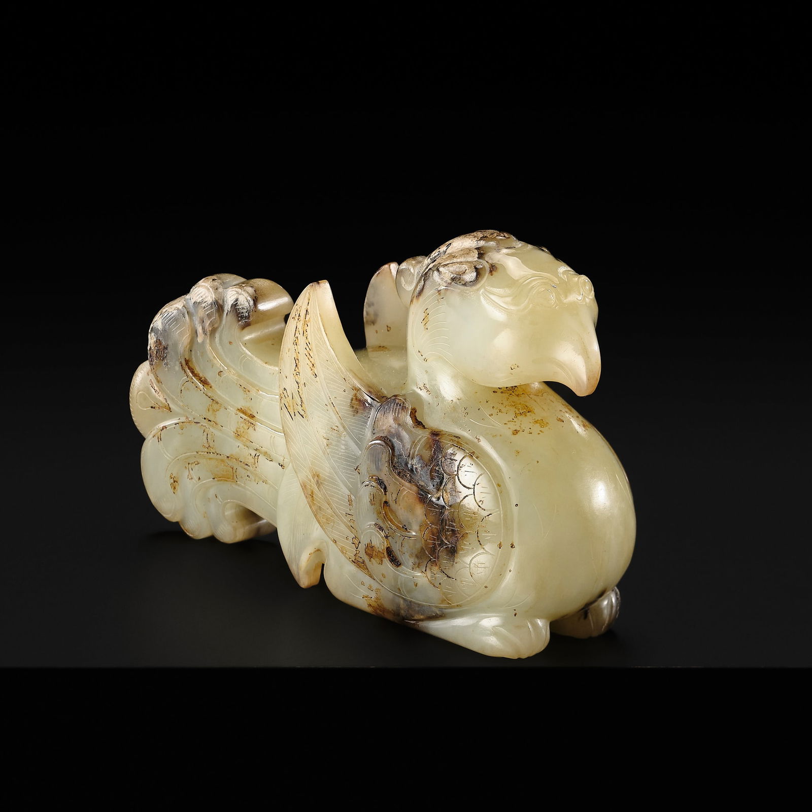 A JADE FIGURE OF A PHOENIX, HAN DYNASTY: A JADE FIGURE OF A PHOENIX, HAN DYNASTY China, 206 BC-220 AD. The translucent stone of an attractive pale greenish-yellow tone with russet speckles and shadings, particularly prominent on the wings,