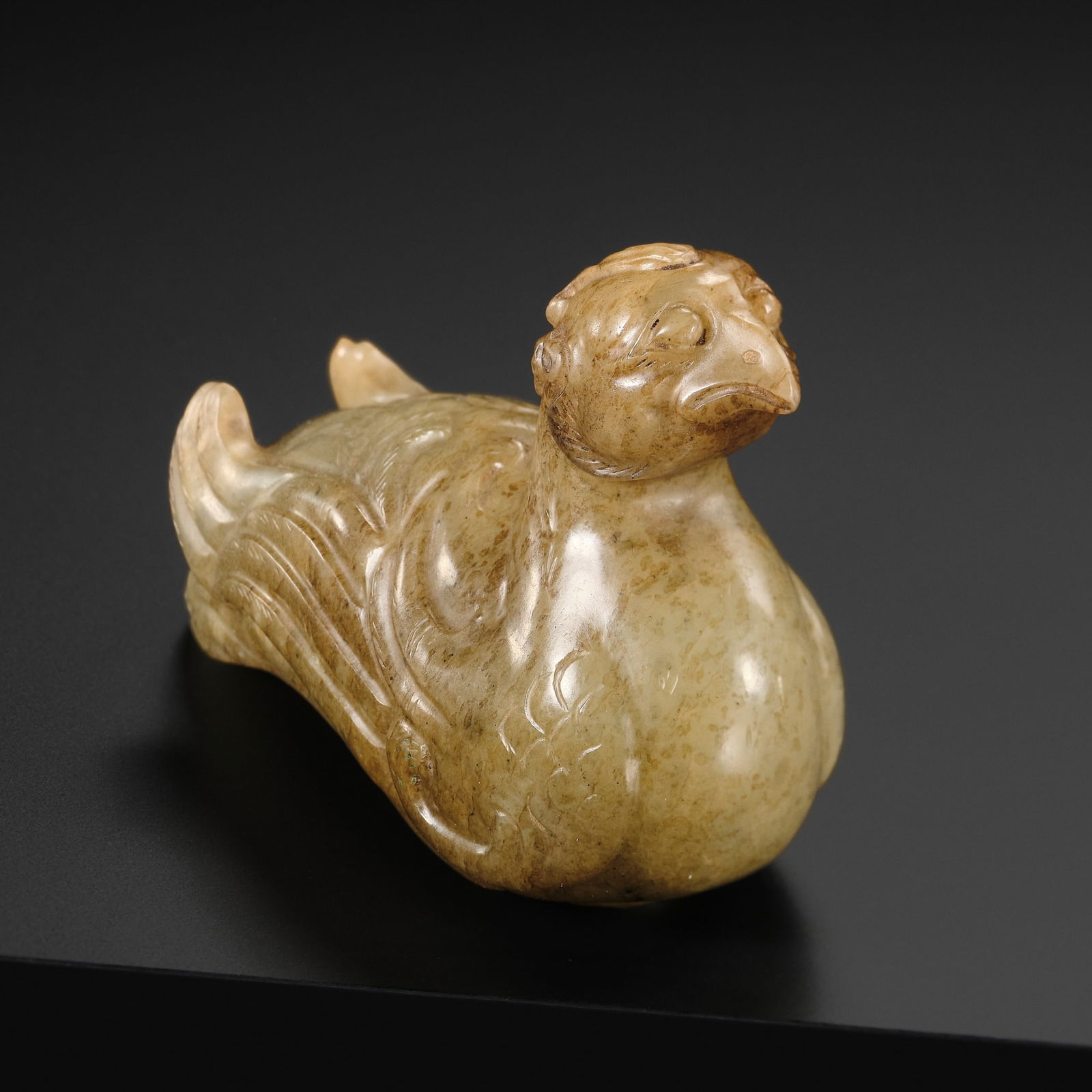 A PALE CELADON AND BROWN JADE STAFF FINIAL IN THE FORM OF A BIRD, SONG DYNASTY: A PALE CELADON AND BROWN JADE STAFF FINIAL IN THE FORM OF A BIRD, SONG DYNASTY China, 960-1279. Magnificently carved, the elongated body of the animal with neatly incised curls and finely modeled win