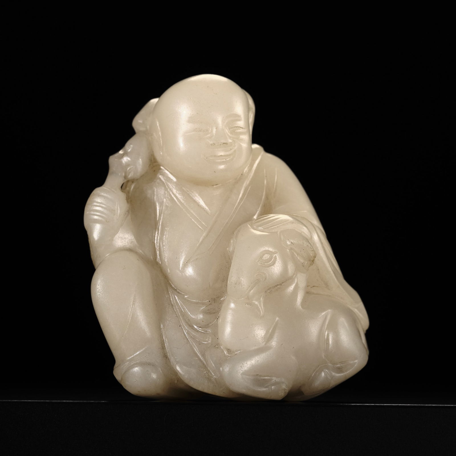 A 'MUTTON FAT' JADE FIGURE OF A BOY WITH A RAM, QING DYNASTY: A 'MUTTON FAT' JADE FIGURE OF A BOY WITH A RAM, QING DYNASTY China, 18th century. Superbly carved as a crouching boy with an amiable expression, dressed in loose-fitting robes and holding a lingzhi s