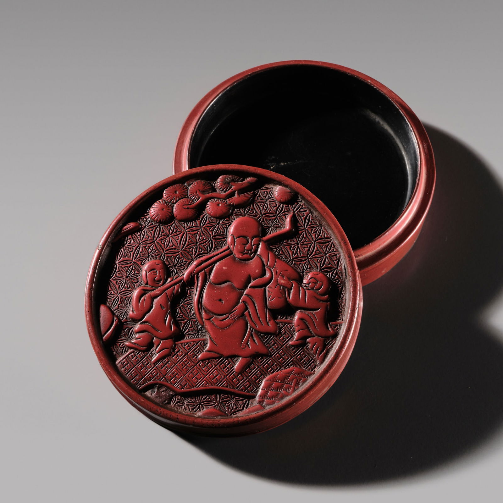 A CINNABAR-LACQUER 'BUDAI AND BOYS' BOX AND COVER, MING DYNASTY (1 of 10)