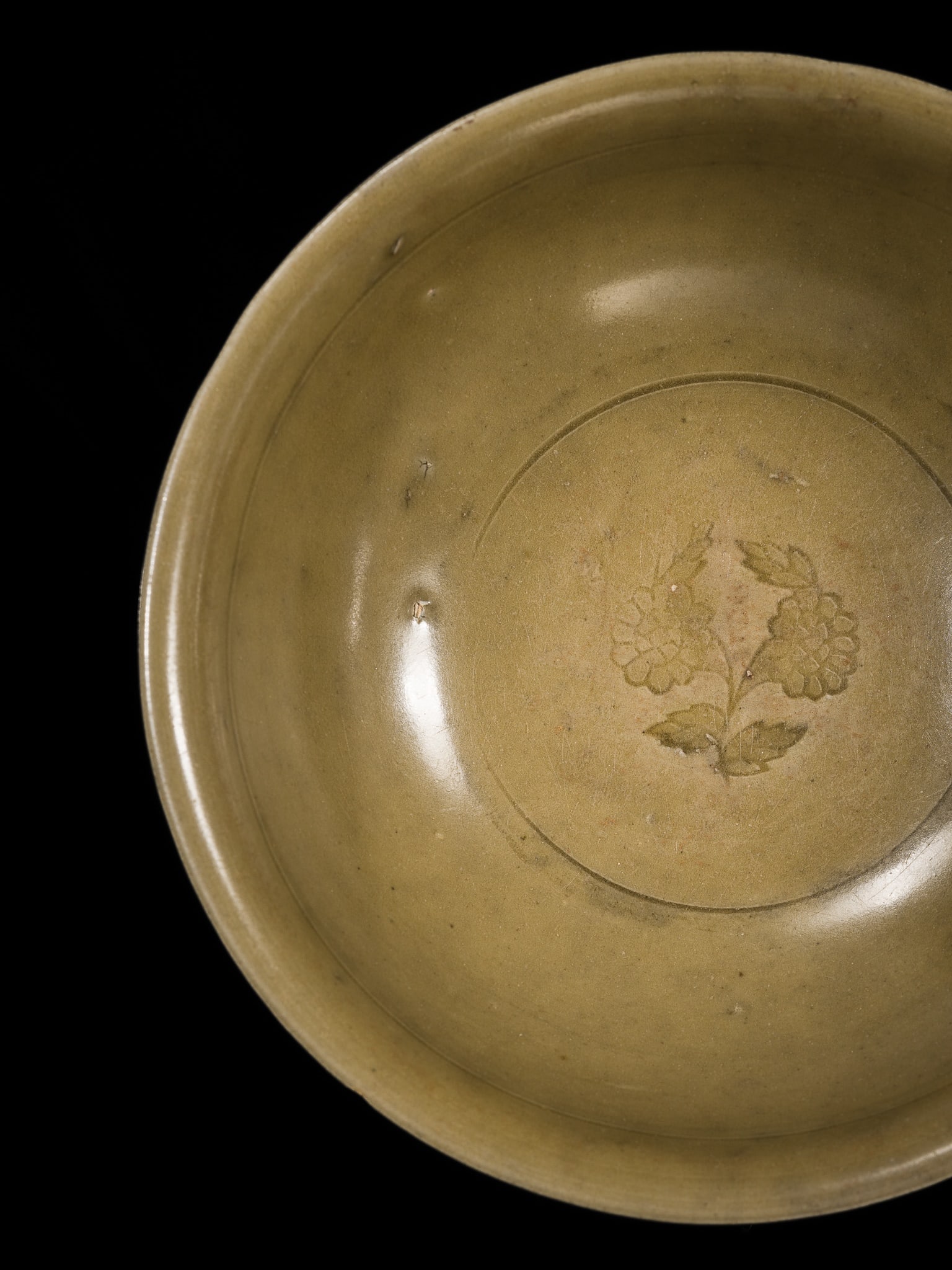 A LONGQUAN CELADON CARVED 'PEONY' BOWL, YUAN-MING DYNASTY: A LONGQUAN CELADON CARVED 'PEONY' BOWL, YUAN-MING DYNASTY China, circa 14th to 15th century. Finely potted with deep, rounded sides supported on a short foot to a broad and slight