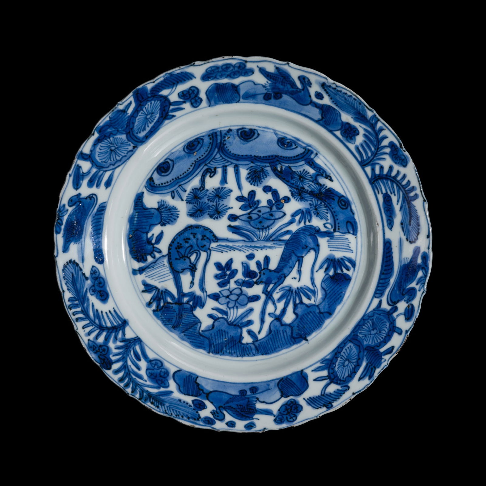 A BLUE AND WHITE 'KRAAK' PORCELAIN DISH WITH DEER IN FOREST, MING DYNASTY, WANLI PERIOD: A BLUE AND WHITE 'KRAAK' PORCELAIN DISH WITH DEER IN FOREST, MING DYNASTY, WANLI PERIOD China, 1572-1620. Well-potted, with shallow, rounded sides rising from a short, tapered foot with a recessed
