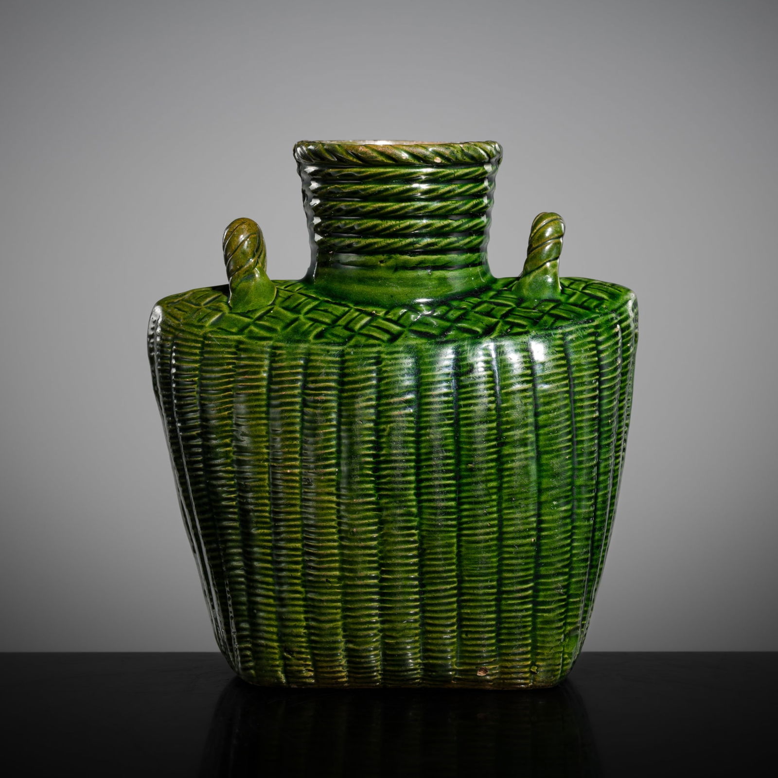 AN EMERALD-GREEN GLAZED 'WICKER BASKET' POTTERY VASE, LATE MING: AN EMERALD-GREEN GLAZED 'WICKER BASKET' POTTERY VASE, LATE MING China, circa 17th century. Finely modeled in the form of a wicker basket, with a flattened, trapezoidal body, rising to high-an