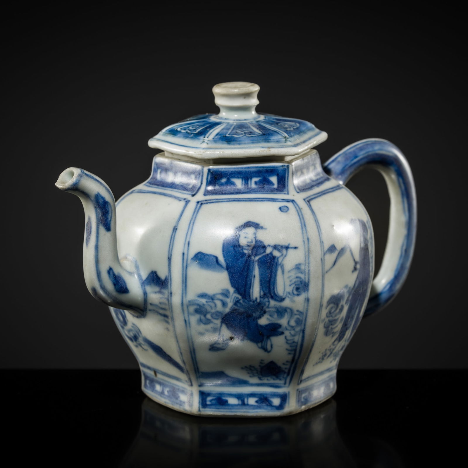 A RARE BLUE AND WHITE 'IMMORTALS' TEAPOT, TRANSITIONAL PERIOD, FROM THE HATCHER CARGO: A RARE BLUE AND WHITE 'IMMORTALS' TEAPOT, TRANSITIONAL PERIOD, FROM THE HATCHER CARGO China, mid-17th century. The short foot rising to a faceted baluster body, applied on either side with a C-form h