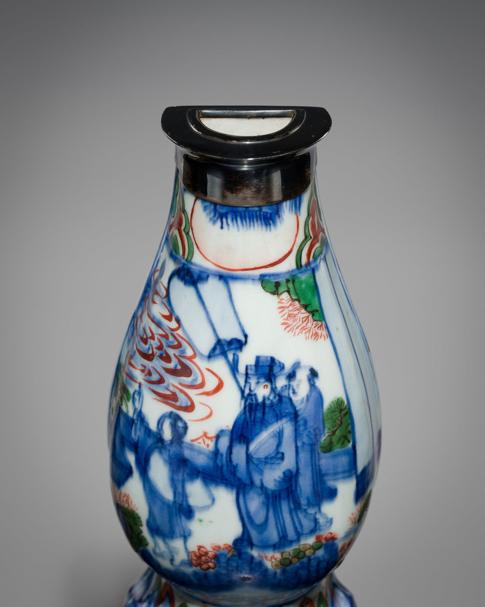 A WUCAI, SILVER-MOUNTED, PORCELAIN 'SCHOLARS IN GARDEN' WALL VASE, TRANSITIONAL PERIOD: A WUCAI, SILVER-MOUNTED, PORCELAIN 'SCHOLARS IN GARDEN' WALL VASE, TRANSITIONAL PERIOD China, 17th century. Well-potted, the flat-backed baluster body rising from a splayed foot to an elongated, gent