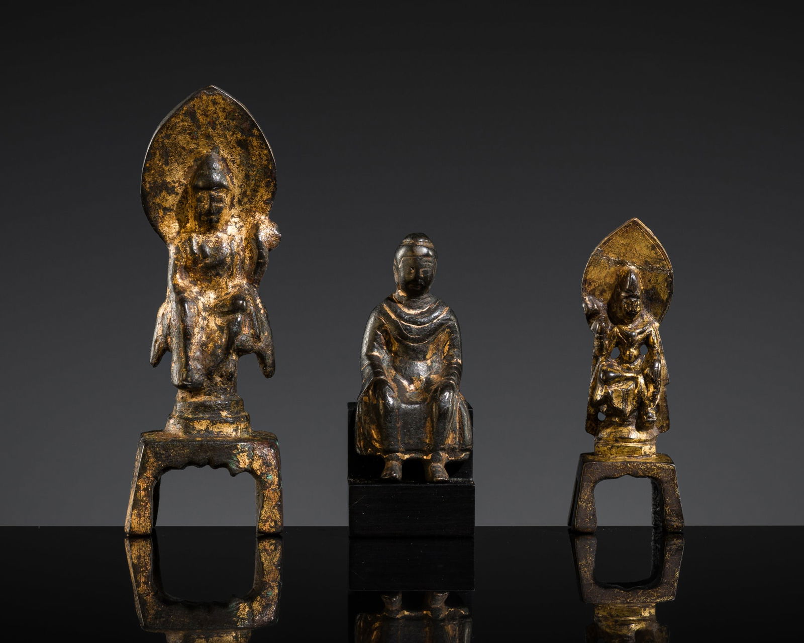 A GROUP LOT WITH THREE GILT-BRONZE BUDDHIST FIGURES, SUI TO TANG DYNASTY: A GROUP LOT WITH THREE GILT-BRONZE BUDDHIST FIGURES, SUI TO TANG DYNASTY China, 581-906. Each boldly cast, two of them raised upon a four-legged support and their heads distinctively nimbated with a