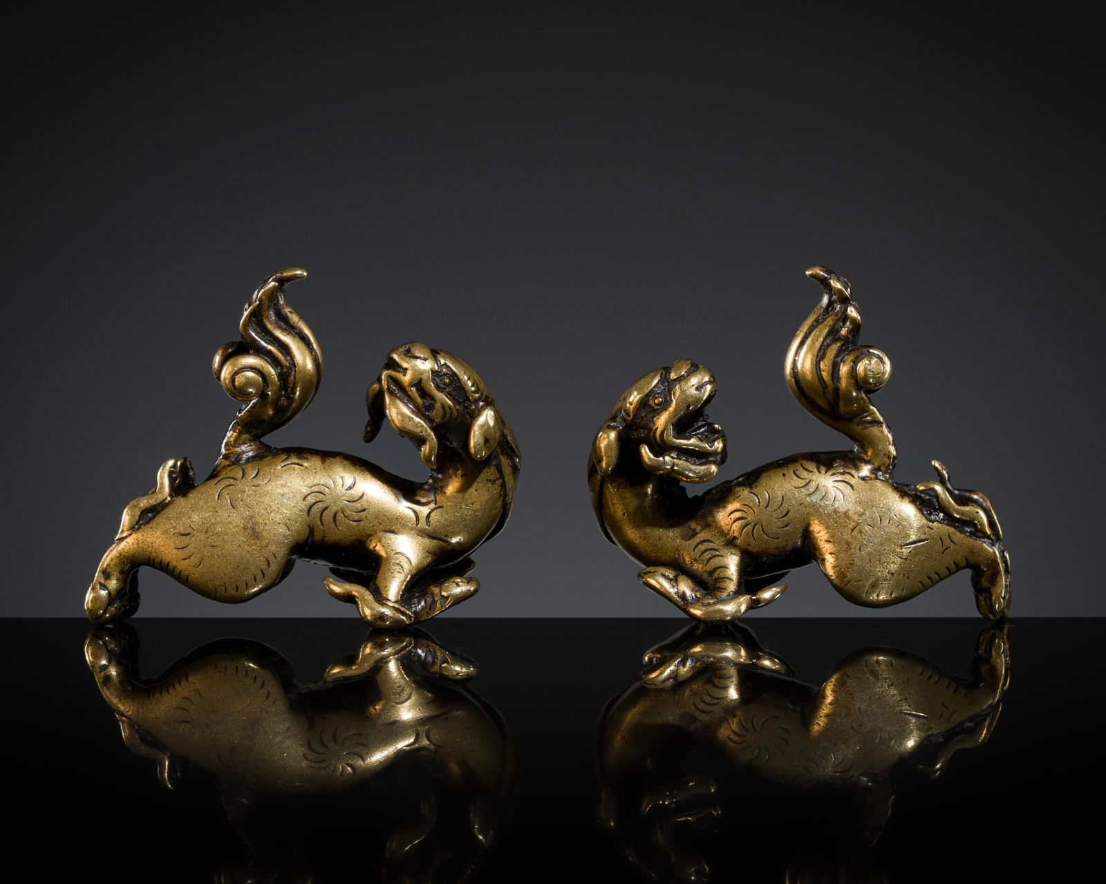 A PAIR OF SMALL GILT-BRONZE 'GUARDIAN LION' WEIGHTS, MING TO EARLY QING DYNASTY: A PAIR OF SMALL GILT-BRONZE 'GUARDIAN LION' WEIGHTS, MING TO EARLY QING DYNASTY China, circa 16th-18th century. Each finely and symmetrically cast, the stylized mythical animals depicted striding wit
