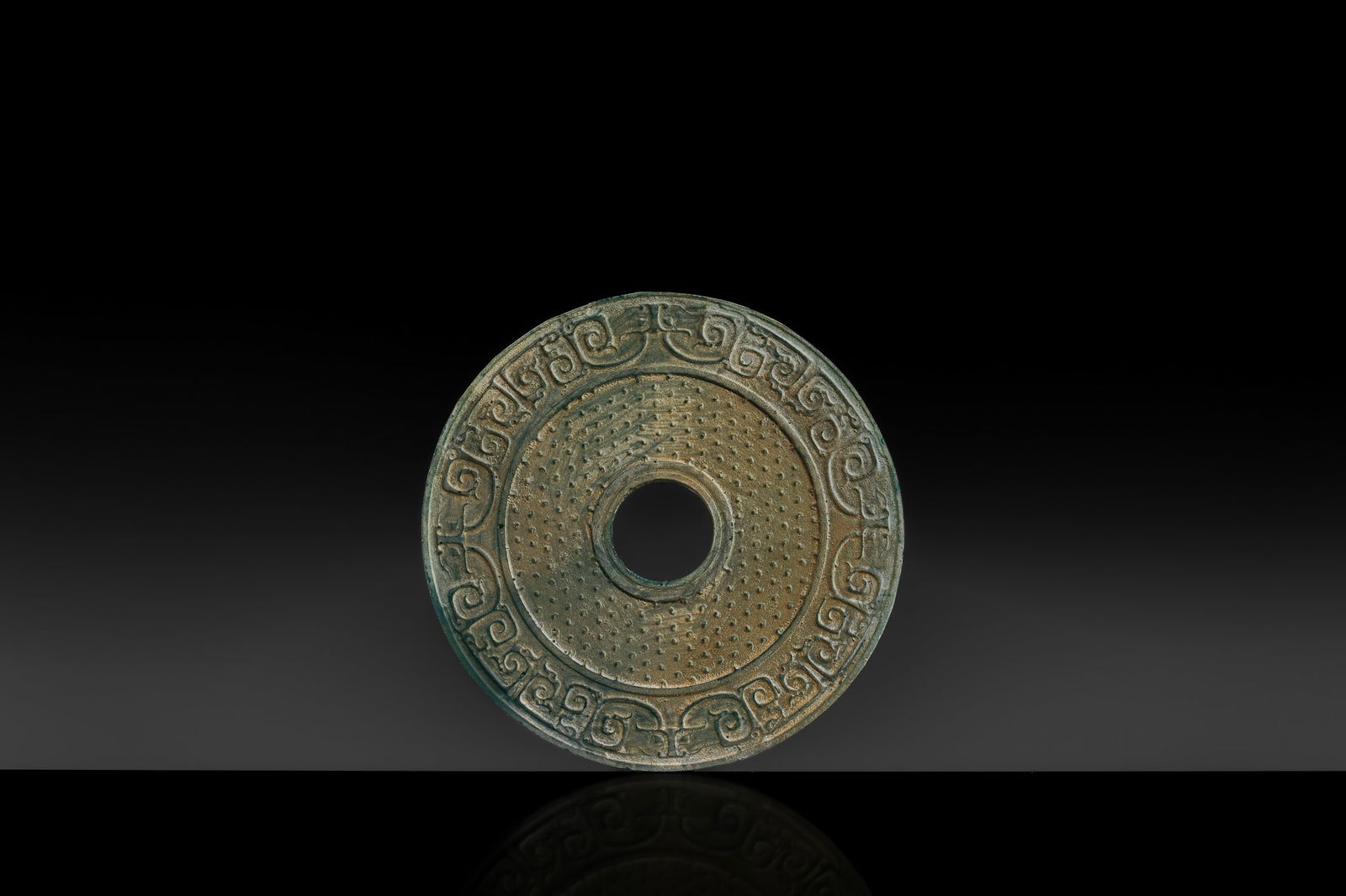 A VERY RARE AQUAMARINE-BLUE GLASS 'TAOTIE AND DRAGON' DISC (BI), WESTERN HAN DYNASTY: A VERY RARE AQUAMARINE-BLUE GLASS 'TAOTIE AND DRAGON' DISC (BI), WESTERN HAN DYNASTY China, 206 BC-8 AD. Of circular form with a central aperture, each side finely carved with an inner band of raised