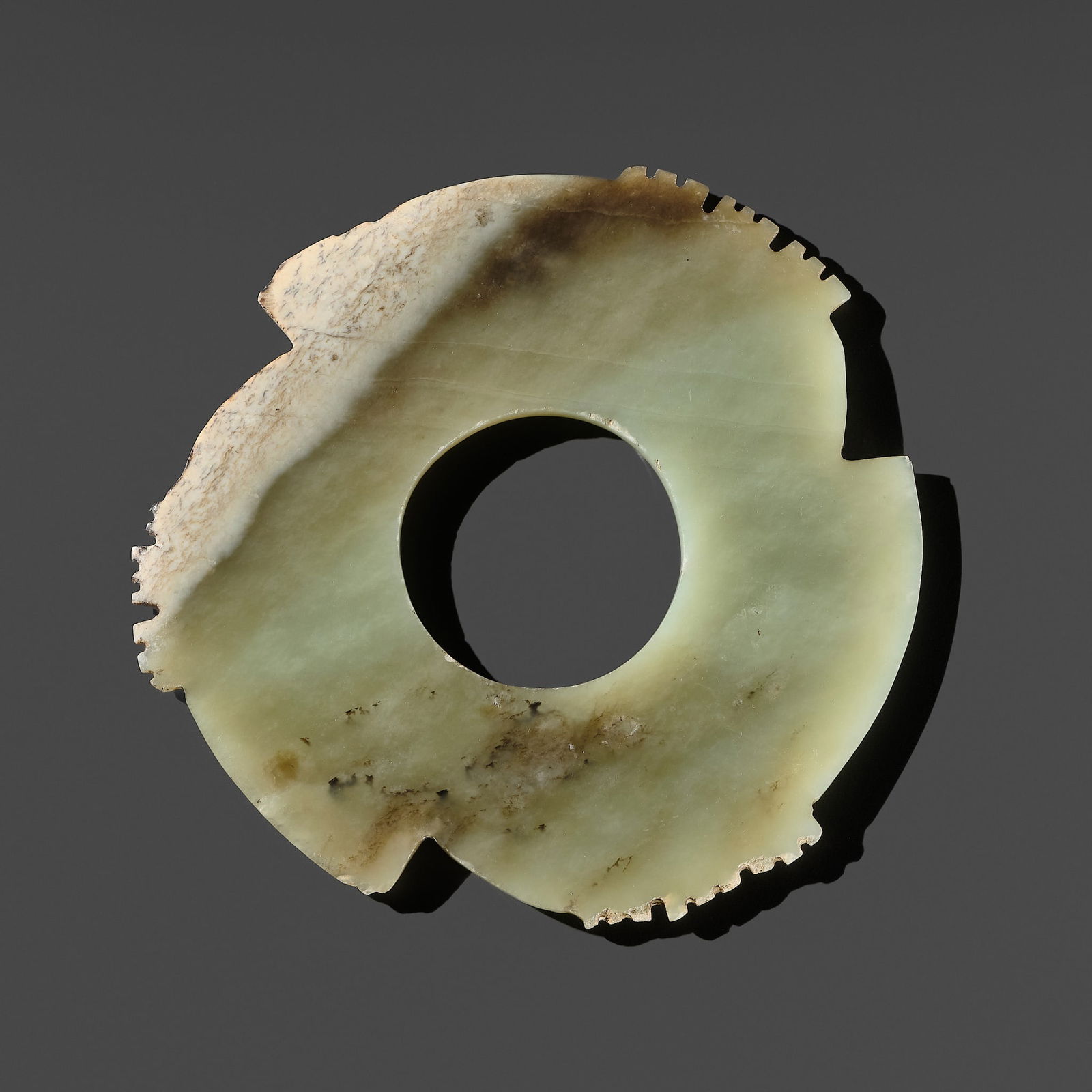 A FINE PALE CELADON AND BROWN JADE NOTCHED DISK (YABI), LATE NEOLITHIC PERIOD, DAWENKOU OR LONGSHAN (1 of 13)
