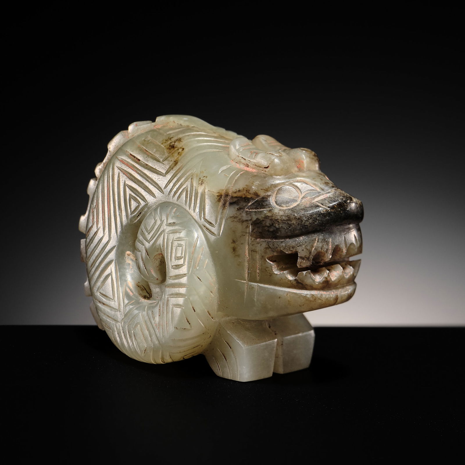 AN EXTREMELY RARE CELADON JADE CARVING OF A DRAGON, LATE SHANG DYNASTY: AN EXTREMELY RARE CELADON JADE CARVING OF A DRAGON, LATE SHANG DYNASTY China, c. 13th-11th century BC. Boldly carved in the round as a stylized dragon, with a bifurcated tail, with each terminal coil