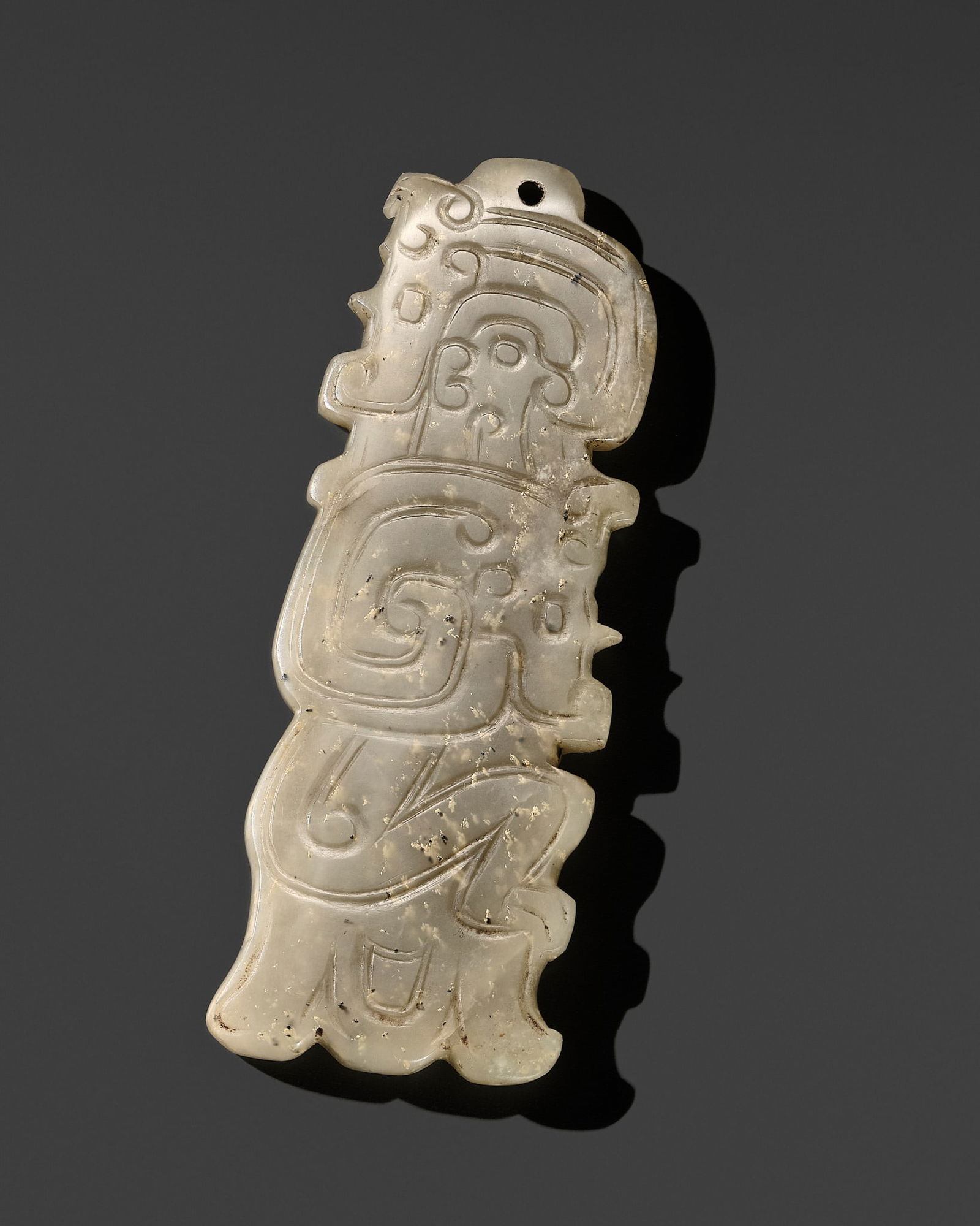 A SMALL WHITE JADE 'HUMANOID AND ANIMAL' PENDANT, LATE SHANG TO EARLY WESTERN ZHOU DYNASTY: A SMALL WHITE JADE 'HUMANOID AND ANIMAL' PENDANT, LATE SHANG TO EARLY WESTERN ZHOU DYNASTY China, c. 12th-10th century BC. The flattened plaque, of elongated form with irregular contours, finely carv