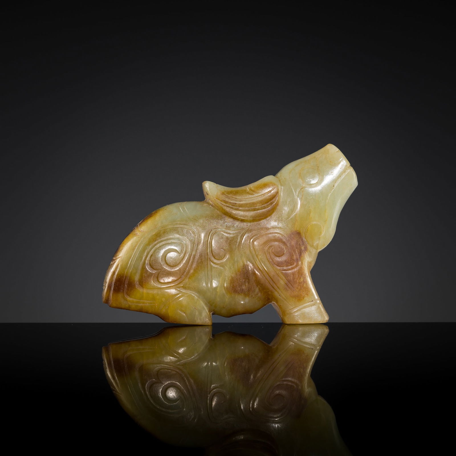 A PALE CELADON AND RUSSET JADE 'WATER BUFFALO' PENDANT, LATE SHANG TO EARLY WESTERN ZHOU DYNASTY: A PALE CELADON AND RUSSET JADE 'WATER BUFFALO' PENDANT, LATE SHANG TO EARLY WESTERN ZHOU DYNASTY China, c. 13th-11th century BC. Finely carved, the recumbent animal, shown in profile, resting on its