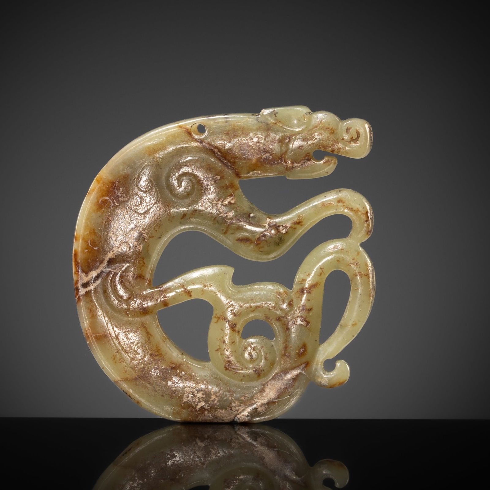 A CELADON AND RUSSET JADE 'DRAGON' PENDANT, EASTERN ZHOU PERIOD (1 of 12)