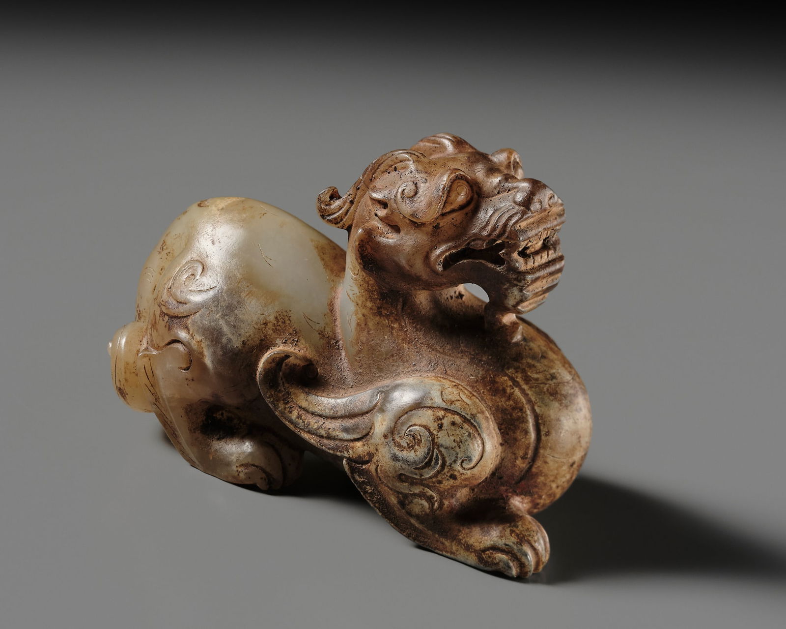 A JADE FIGURE OF A BIXIE, HAN DYNASTY: A JADE FIGURE OF A BIXIE, HAN DYNASTY China, 206 BC-220 AD. Carved as a powerful winged beast in a crouching stance, the right front leg stretched forward, the thick paws appearing to firmly grip the