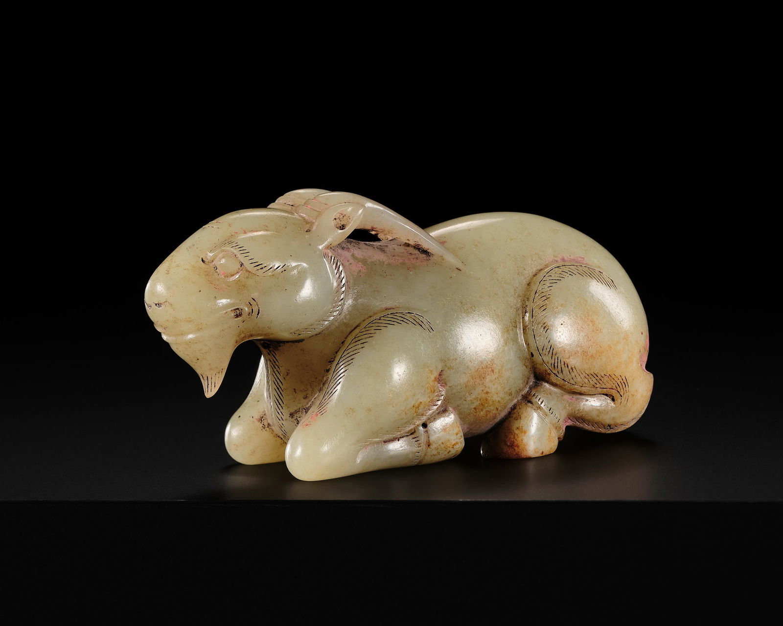 A SUPERB PALE CELADON AND RUSSET JADE CARVING OF A RAM, EASTERN HAN DYNASTY OR LATER: A SUPERB PALE CELADON AND RUSSET JADE CARVING OF A RAM, EASTERN HAN DYNASTY OR LATER China, c. 1st-3rd century AD. Naturalistically carved as a recumbent ram, its four legs folded beneath a plump bod