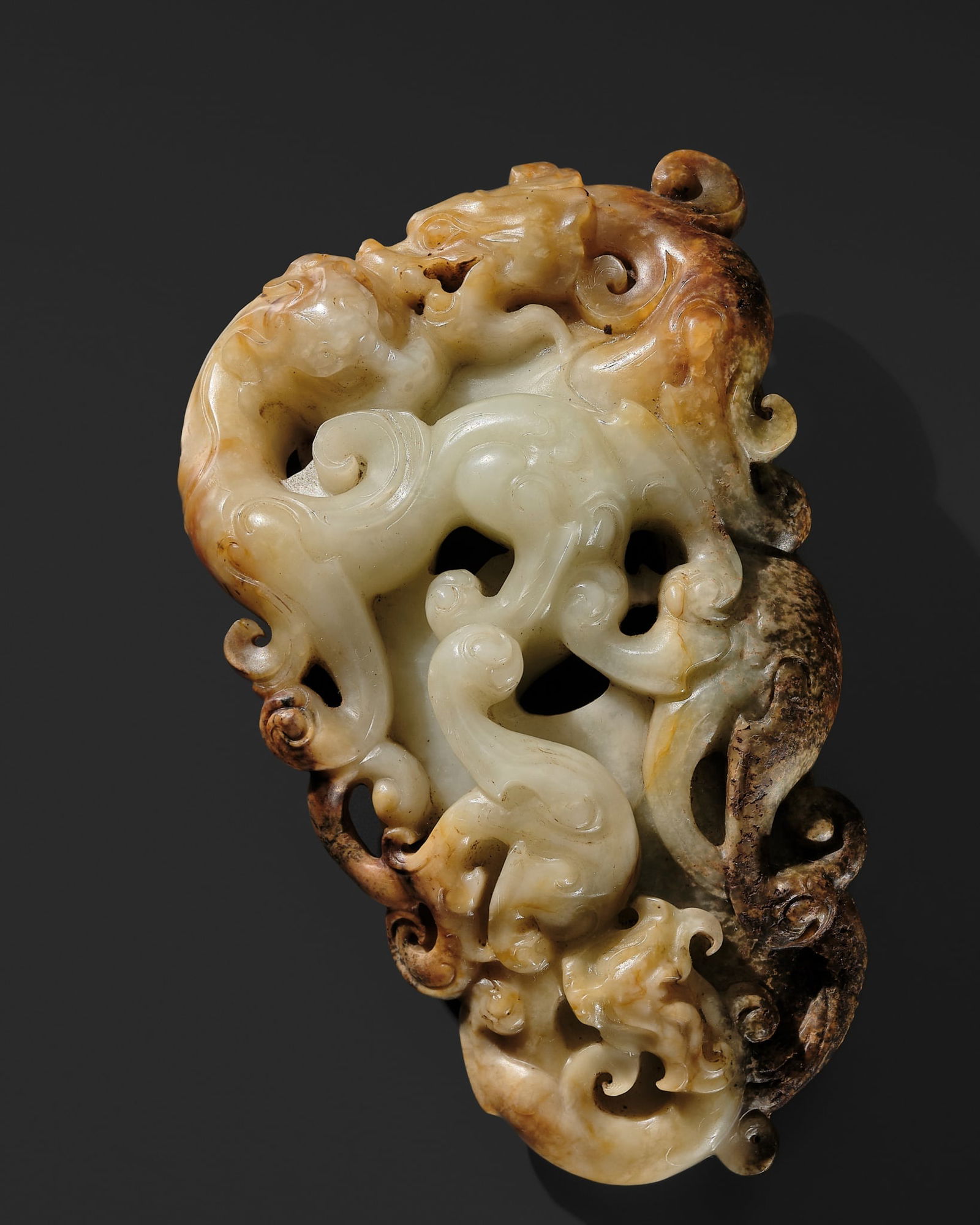 A LARGE PALE CELADON, RUSSET, AND BROWN JADE 'ARCHER'S RING' PENDANT, PEI, HAN DYNASTY: A LARGE PALE CELADON, RUSSET, AND BROWN JADE 'ARCHER'S RING' PENDANT, PEI, HAN DYNASTY China, 206 BC-220 AD. Finely carved in openwork with three sinuous chilong and a dragon encircling an archer's r