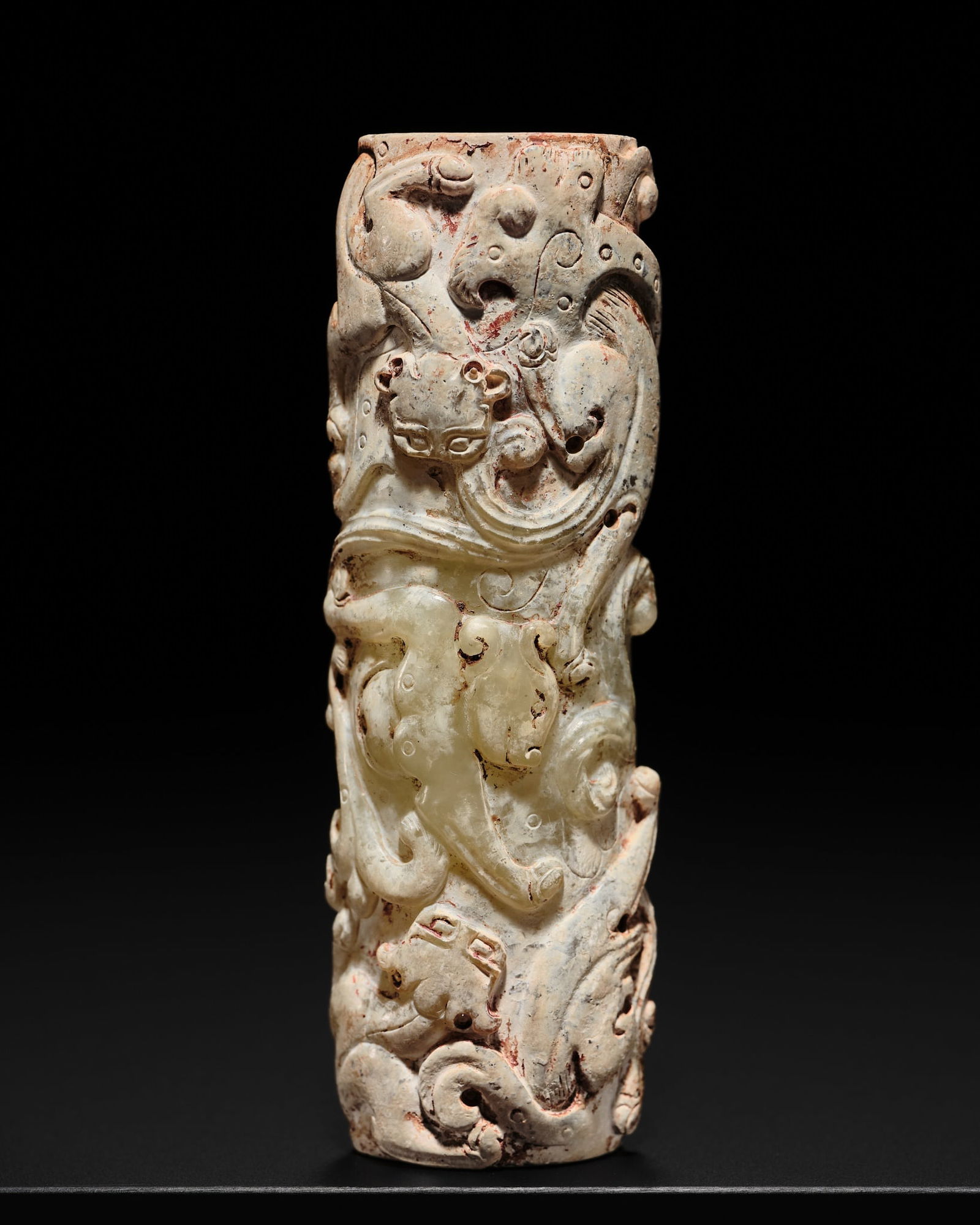 A RARE PALE CELADON JADE 'CHILONG' BEAD, HAN DYNASTY: A RARE PALE CELADON JADE 'CHILONG' BEAD, HAN DYNASTY China, 207 BC-220 AD. The long tubular bead, of irregular oval section, drilled from both sides and skillfully carved on one side with a pair of s