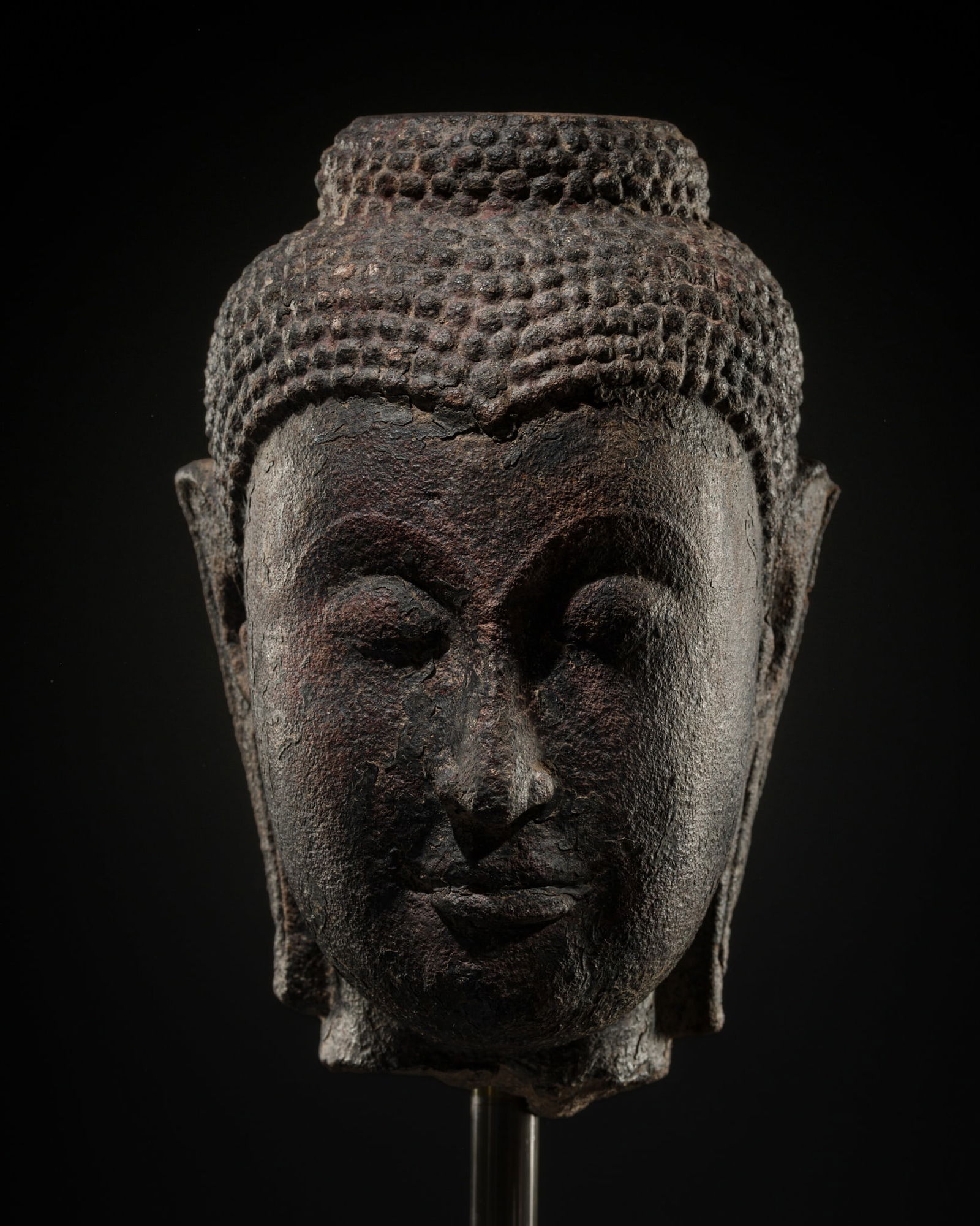 A LACQUERED SANDSTONE HEAD OF AVALOKITESHVARA, AYUTTHAYA, 16TH-17TH CENTURY: A LACQUERED SANDSTONE HEAD OF AVALOKITESHVARA, AYUTTHAYA, 16TH-17TH CENTURY This lot is from a single owner collection and is therefore offered without reserve Exhibited: Museum der Völk