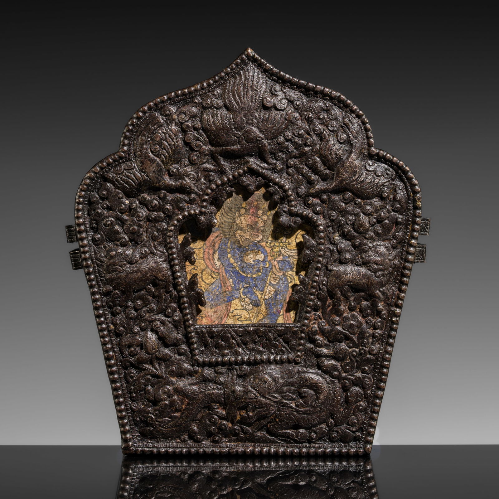 AN IRON PORTABLE SHRINE WITH A TSA-TSA DEPICTING DAKINI SIMHAVAKTRA, GAU, 18TH-19TH CENTURY OR: AN IRON PORTABLE SHRINE WITH A TSA-TSA DEPICTING DAKINI SIMHAVAKTRA, GAU, 18TH-19TH CENTURY OR EARLIER This lot is from a single owner collection and is therefore offered without reserve Tibet. Of arc