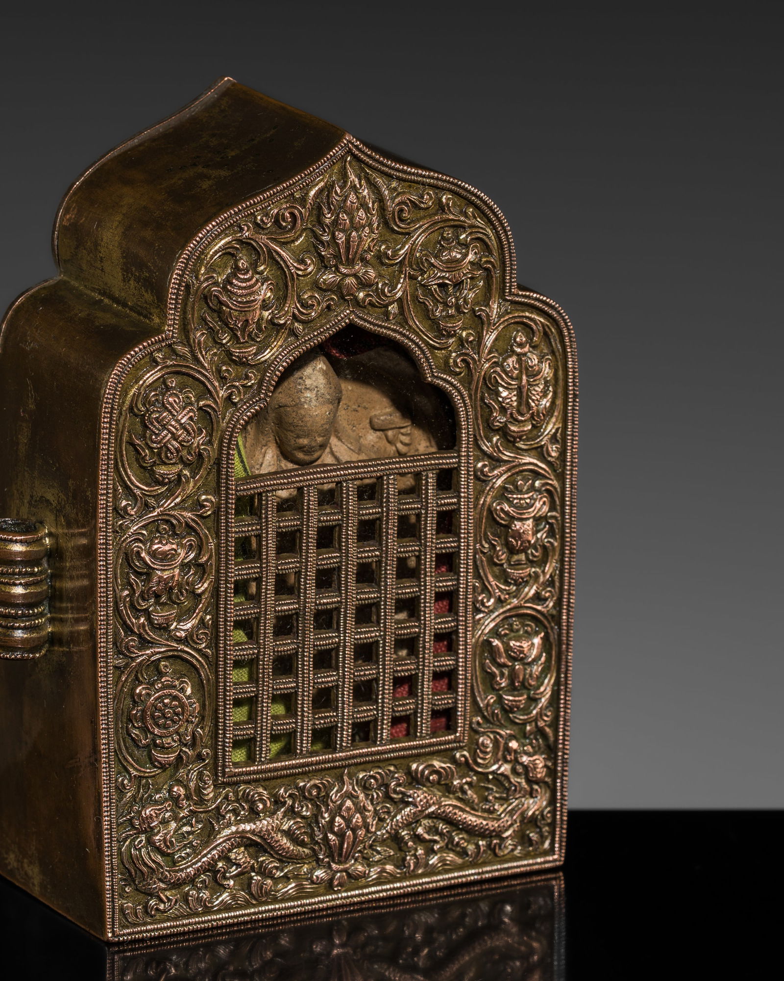 A COPPER PORTABLE SHRINE WITH A CLAY TSA-TSA OF TSONGKHAPA, GAU, 19TH CENTURY: A COPPER PORTABLE SHRINE WITH A CLAY TSA-TSA OF TSONGKHAPA, GAU, 19TH CENTURY This lot is from a single owner collection and is therefore offered without reserve Tibet. Of arched rectangular form, fin