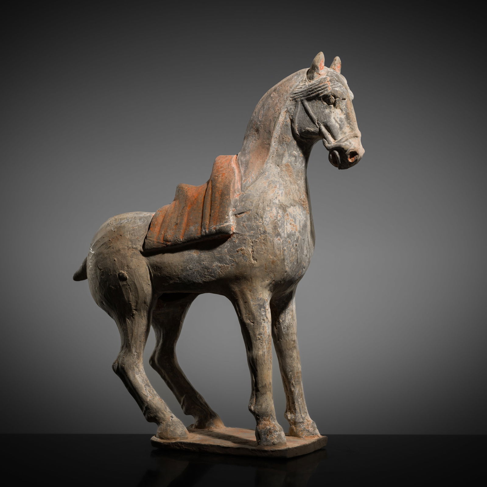 A PAINTED GRAY POTTERY FIGURE OF A HORSE, TANG DYNASTY: A PAINTED GRAY POTTERY FIGURE OF A HORSE, TANG DYNASTY This lot is from a single owner collection and is therefore offered without reserve China, 618-907. A finely modeled horse, standing foursquare o