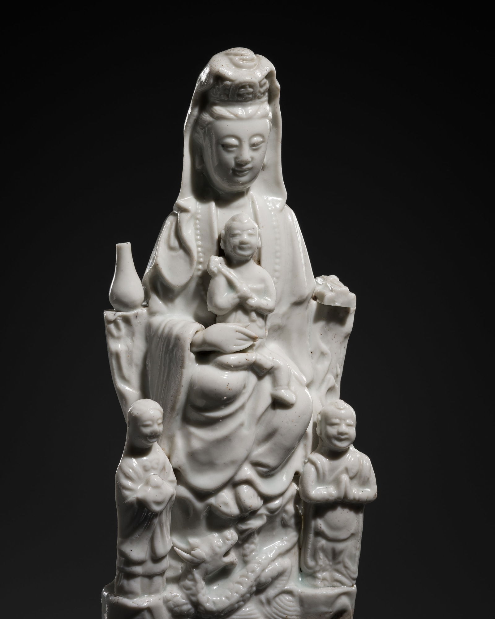 A DEHUA FIGURE OF GUANYIN WITH A CHILD AND ACOLYTES, c. 1920s: A DEHUA FIGURE OF GUANYIN WITH A CHILD AND ACOLYTES, c. 1920s This lot is from a single owner collection and is therefore offered without reserve China, Republic period (1912-1949). Modeled as the