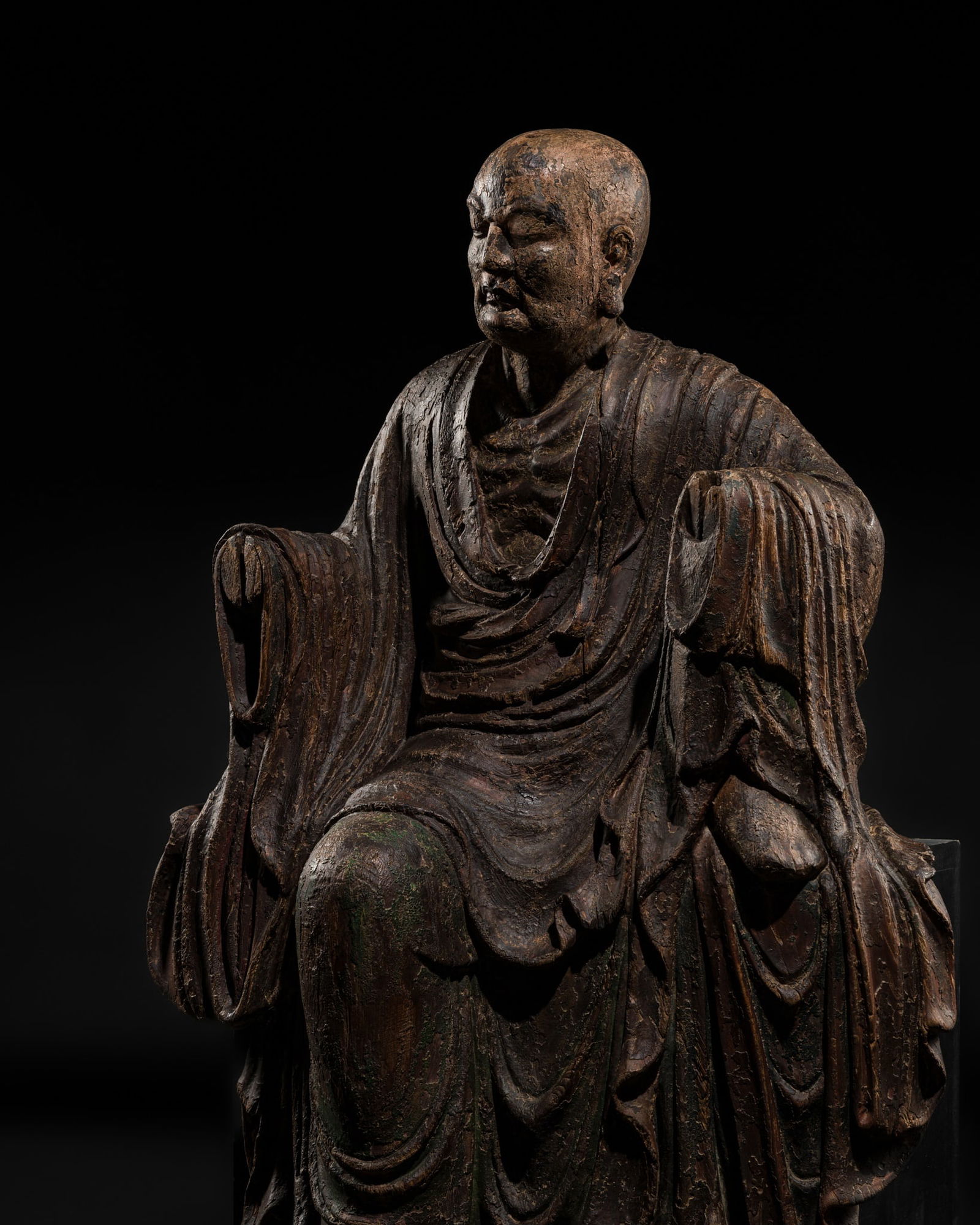 A LARGE POLYCHROME WOOD FIGURE OF BODHIDHARMA AFTER HIS RESURRECTION, EARLY MING DYNASTY: A LARGE POLYCHROME WOOD FIGURE OF BODHIDHARMA AFTER HIS RESURRECTION, EARLY MING DYNASTY China, circa 14th-15th century. Finely carved to depict Damo (Bodhidharma) after he rose from the dead as revea